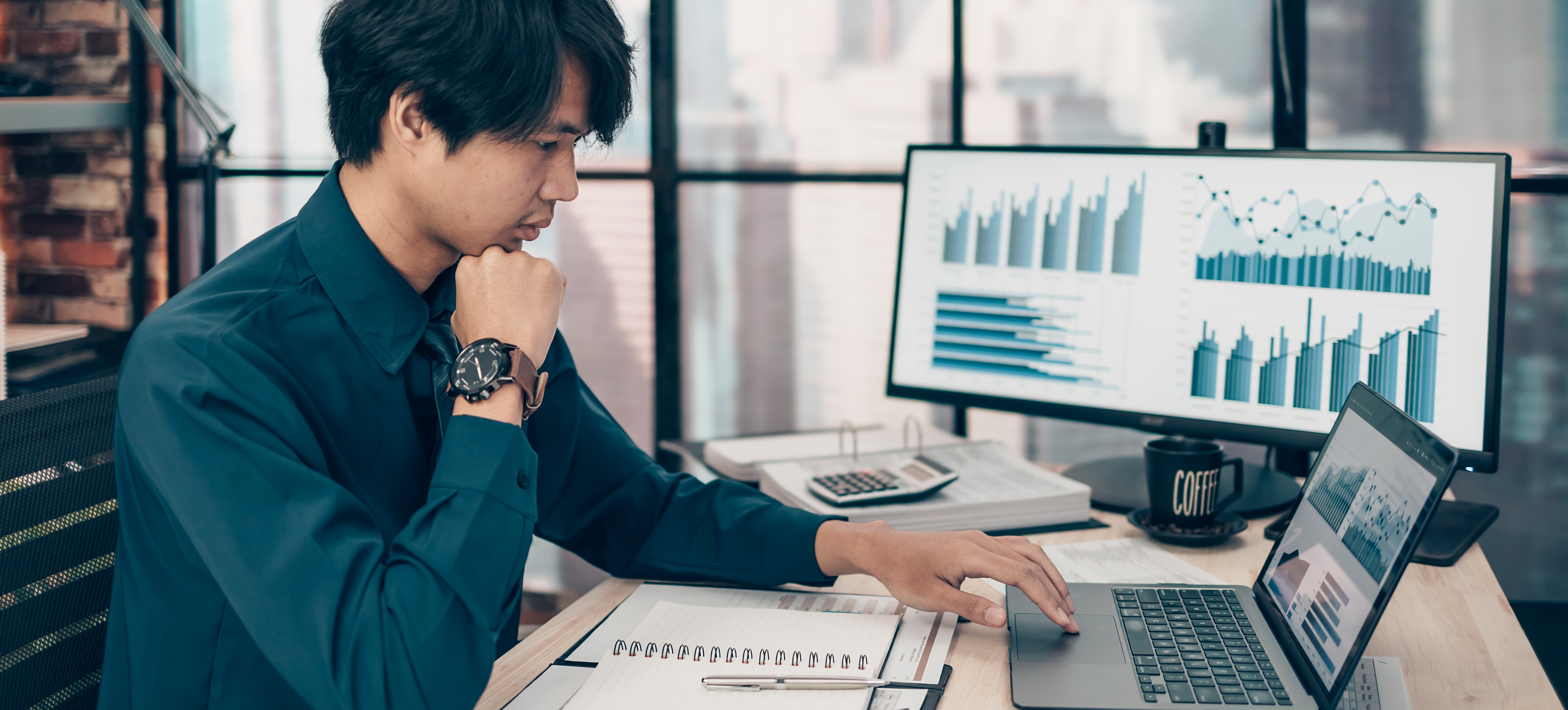 [Featured image]: A person sitting at a desk uses a laptop and monitor to create dynamic charts in Google Sheets.