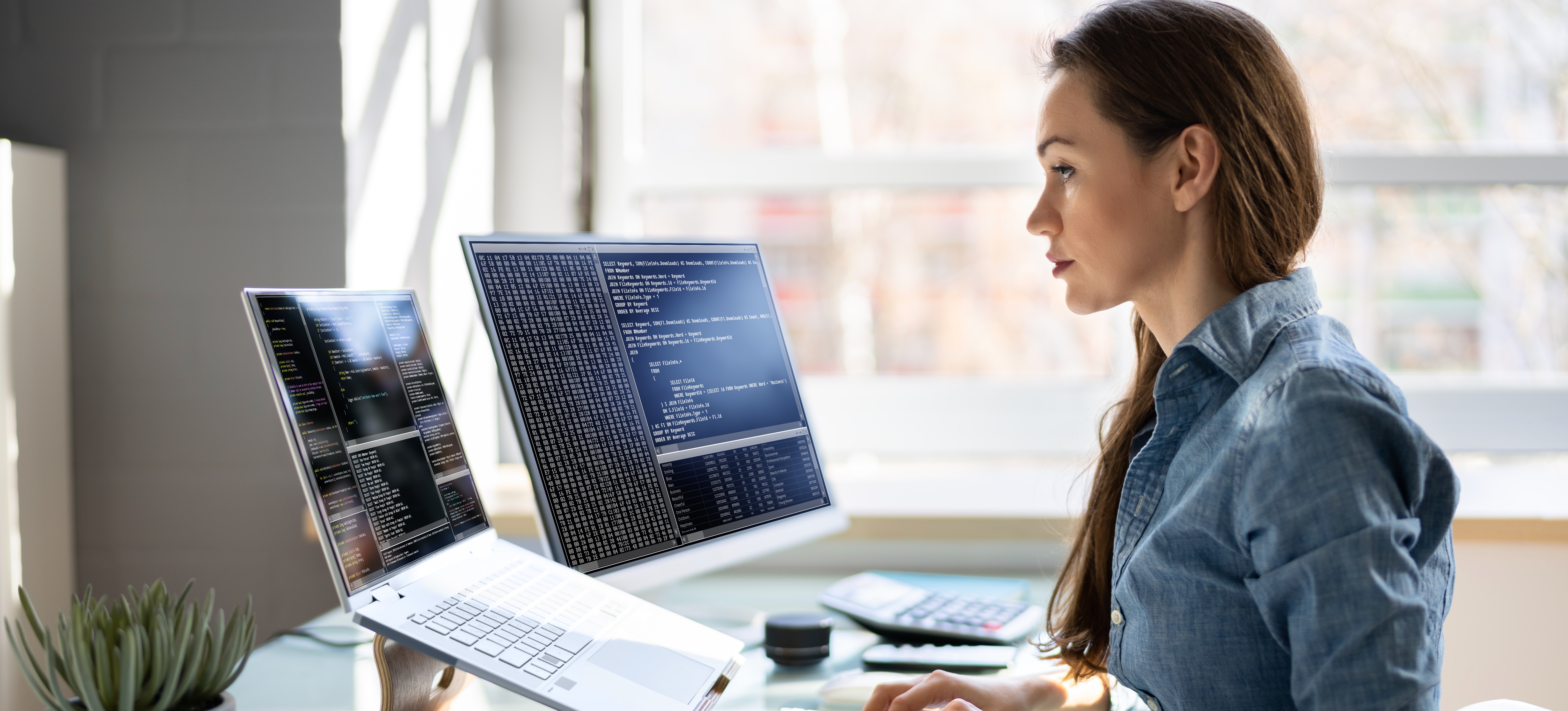 [Featured Image] A machine learning engineer sits in front of a laptop and computer, working on creating a chatbot.