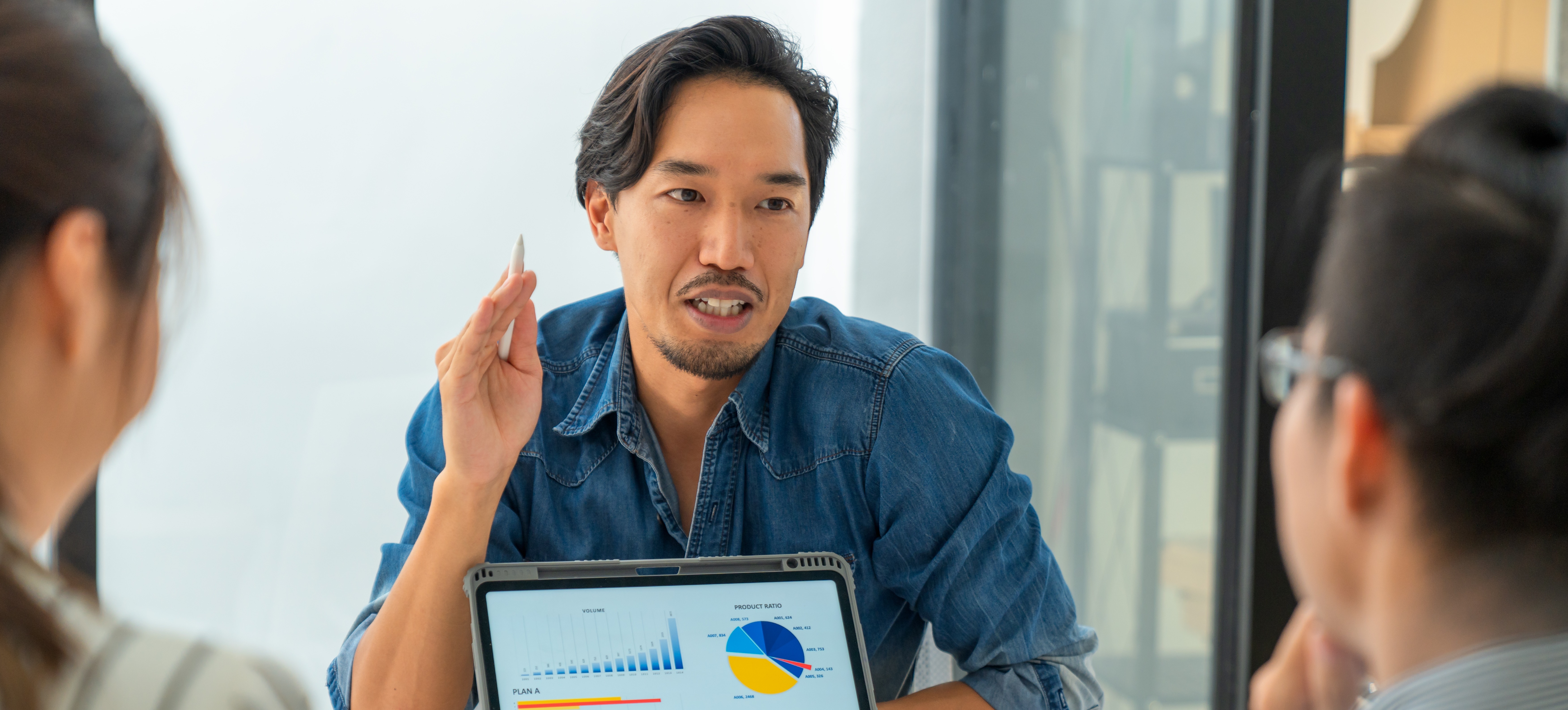 [Featured Image] A data scientist leads a business meeting using data visualization techniques to show the company's production more clearly.