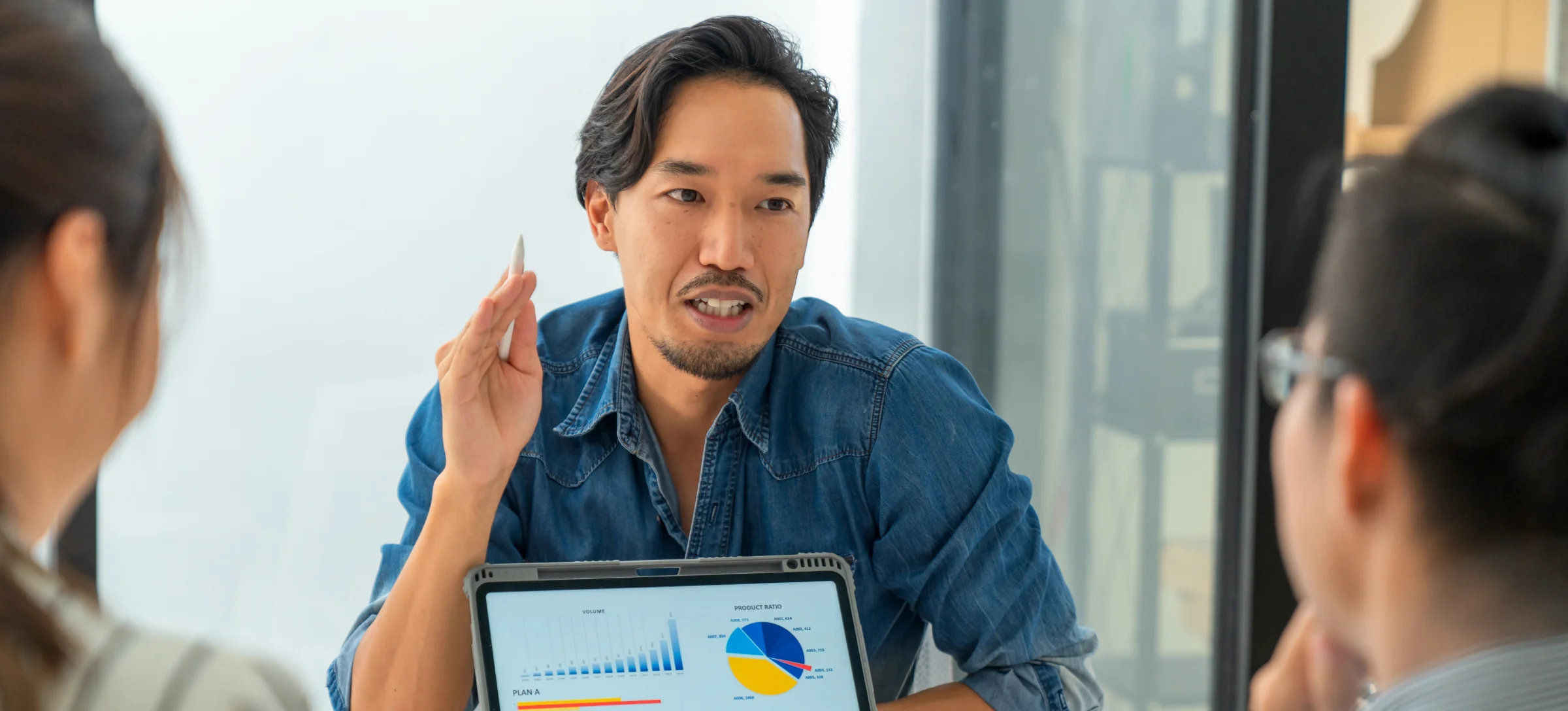 [Featured Image] A data scientist leads a business meeting using data visualization techniques to show the company's production more clearly.