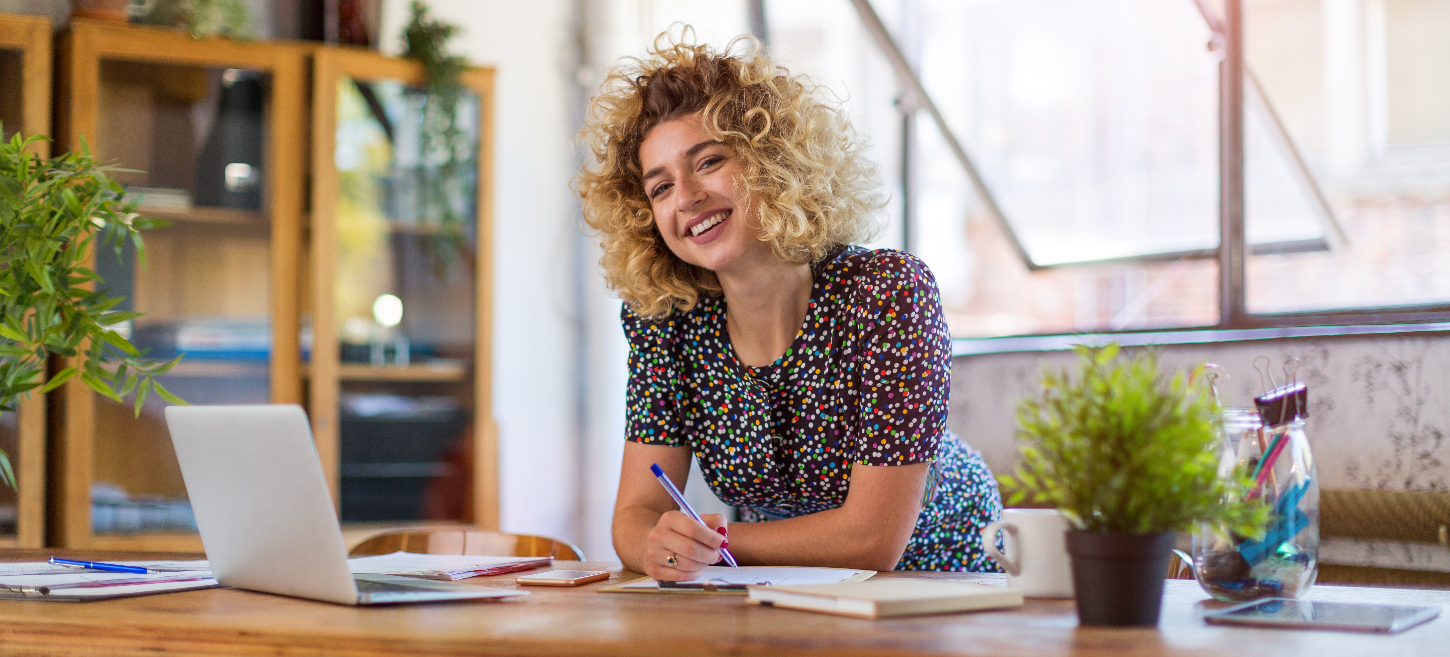 [Featured Image] A woman stands at a laptop computer in an office.