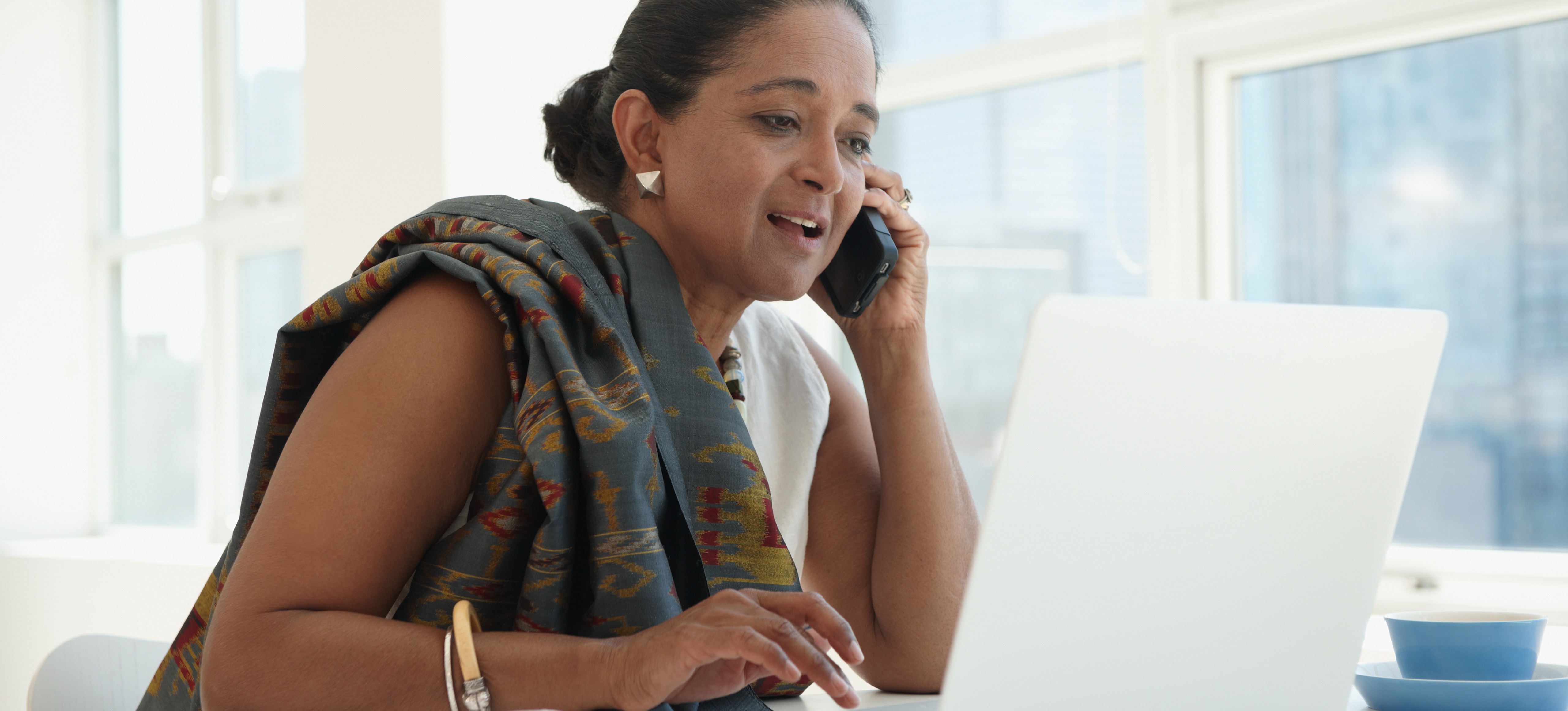 [Featured Image] A data scientist talks on the phone to a colleague whilst using Python in Excel on her laptop.
