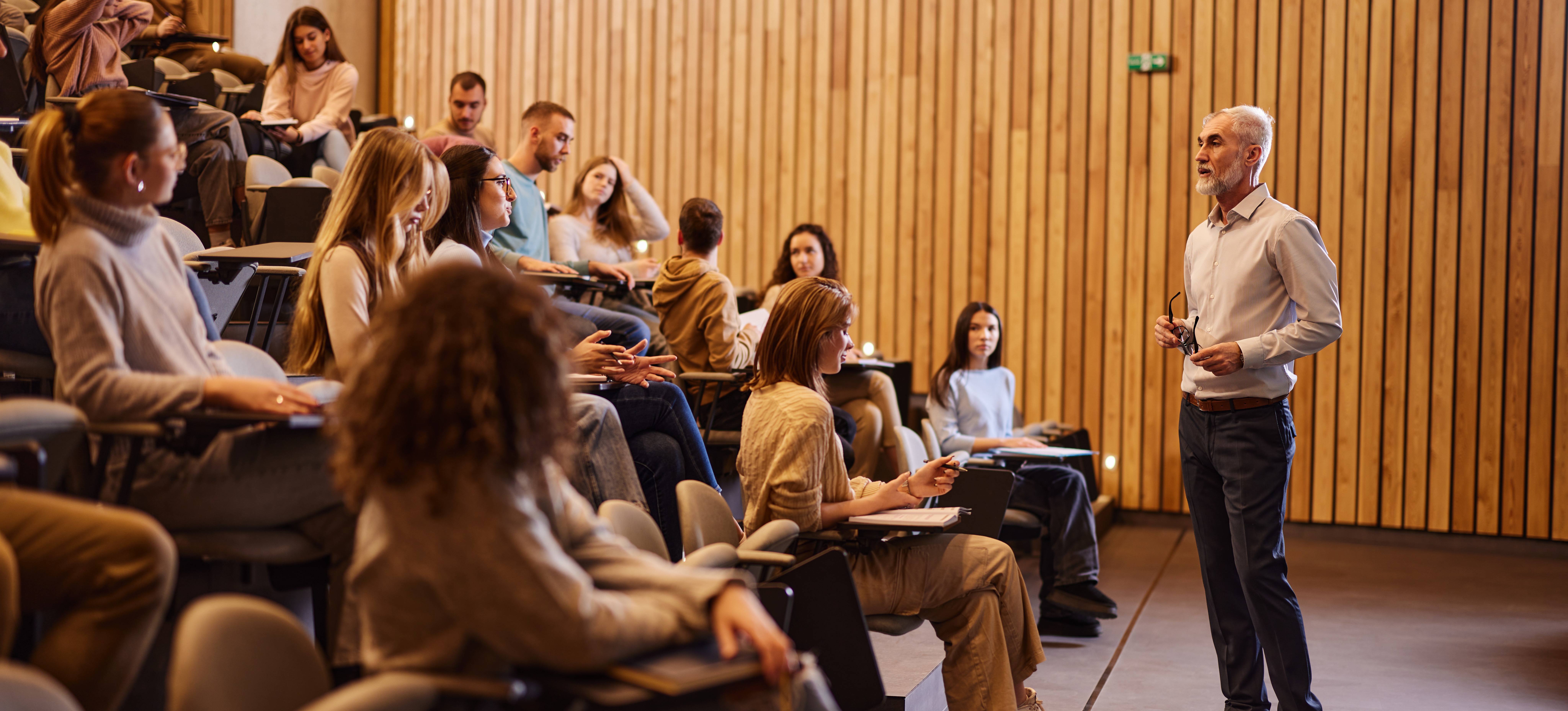 [Featured image]: A professor talks to a room full of students during a lecture about a BA versus a BS degree.