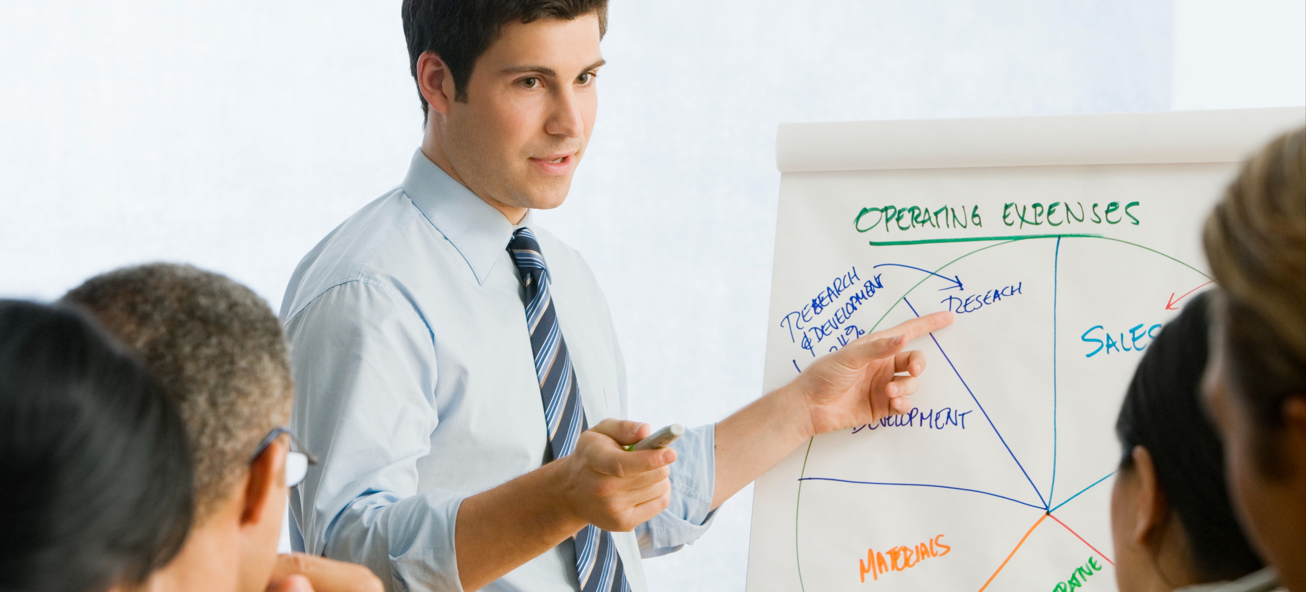 [Image en vedette] Un chef d'entreprise explique des résultats à l'aide d'outils de visualisation de données afin de rendre les informations facilement compréhensibles.

