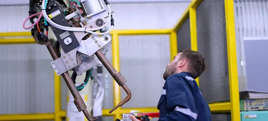[Featured Image] An engineer is programming and supervising a machine learning robotics arm.
