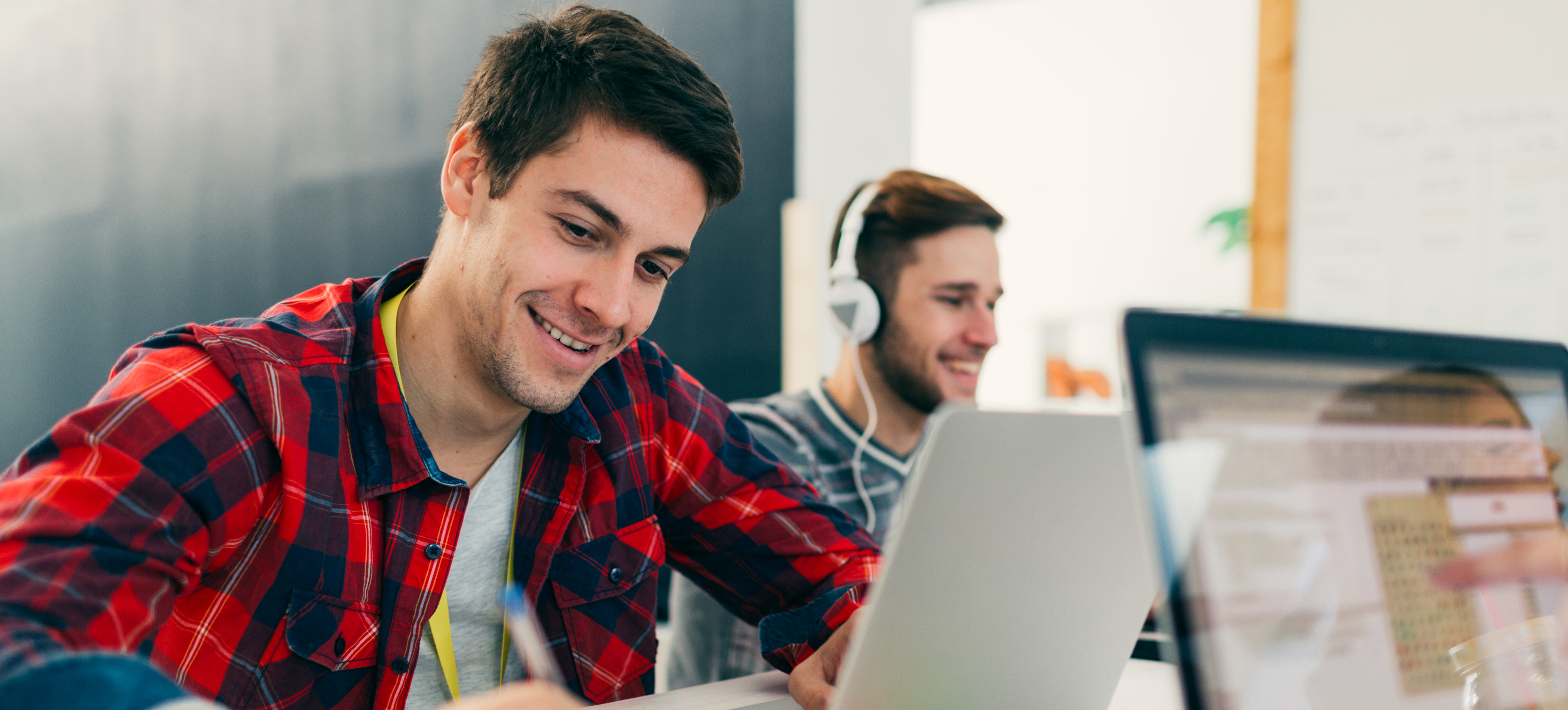[Featured Image] Software developers smiling and taking notes about Hugging Face, a key player in AI and machine learning, in a professional workspace.
