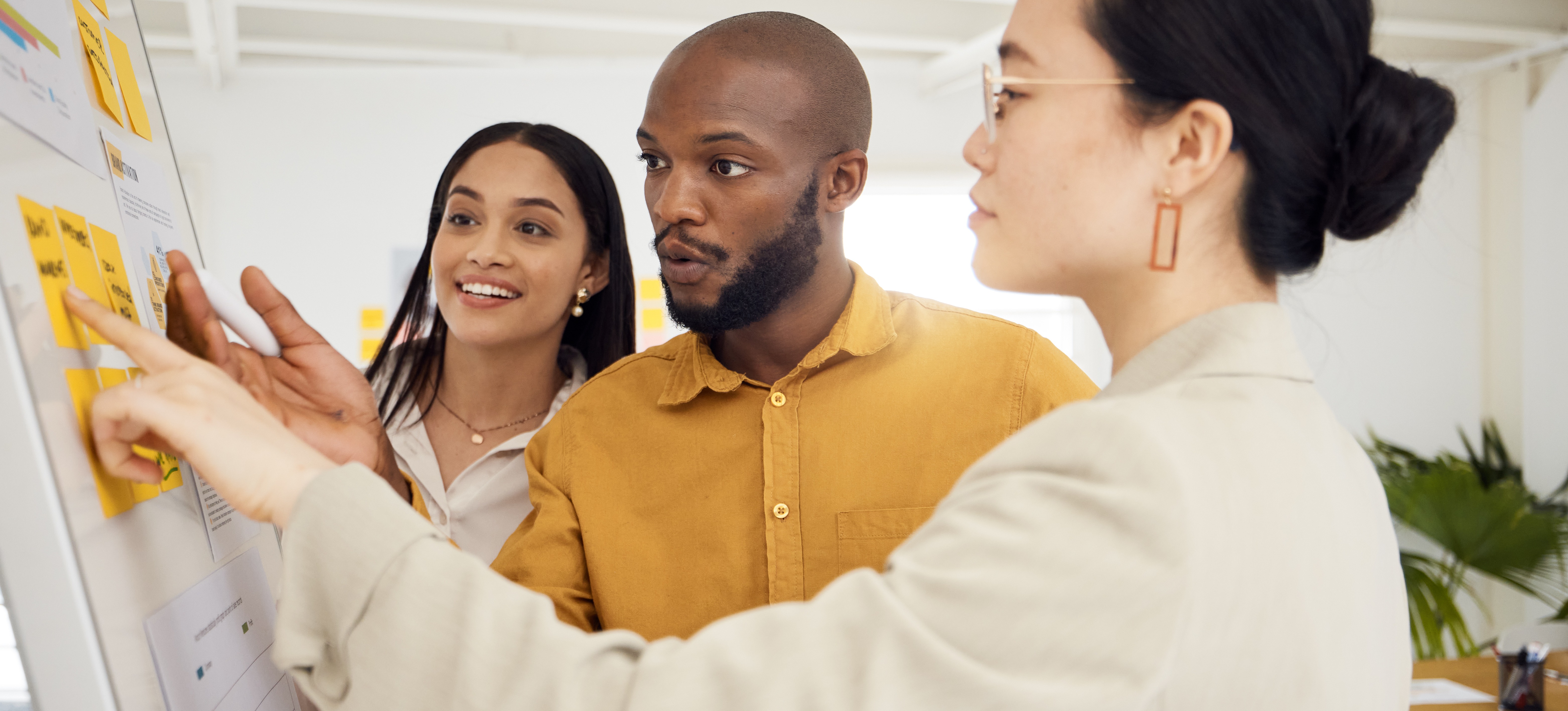 [Featured Image] Three marketers develop a retargeting strategy using a whiteboard.
