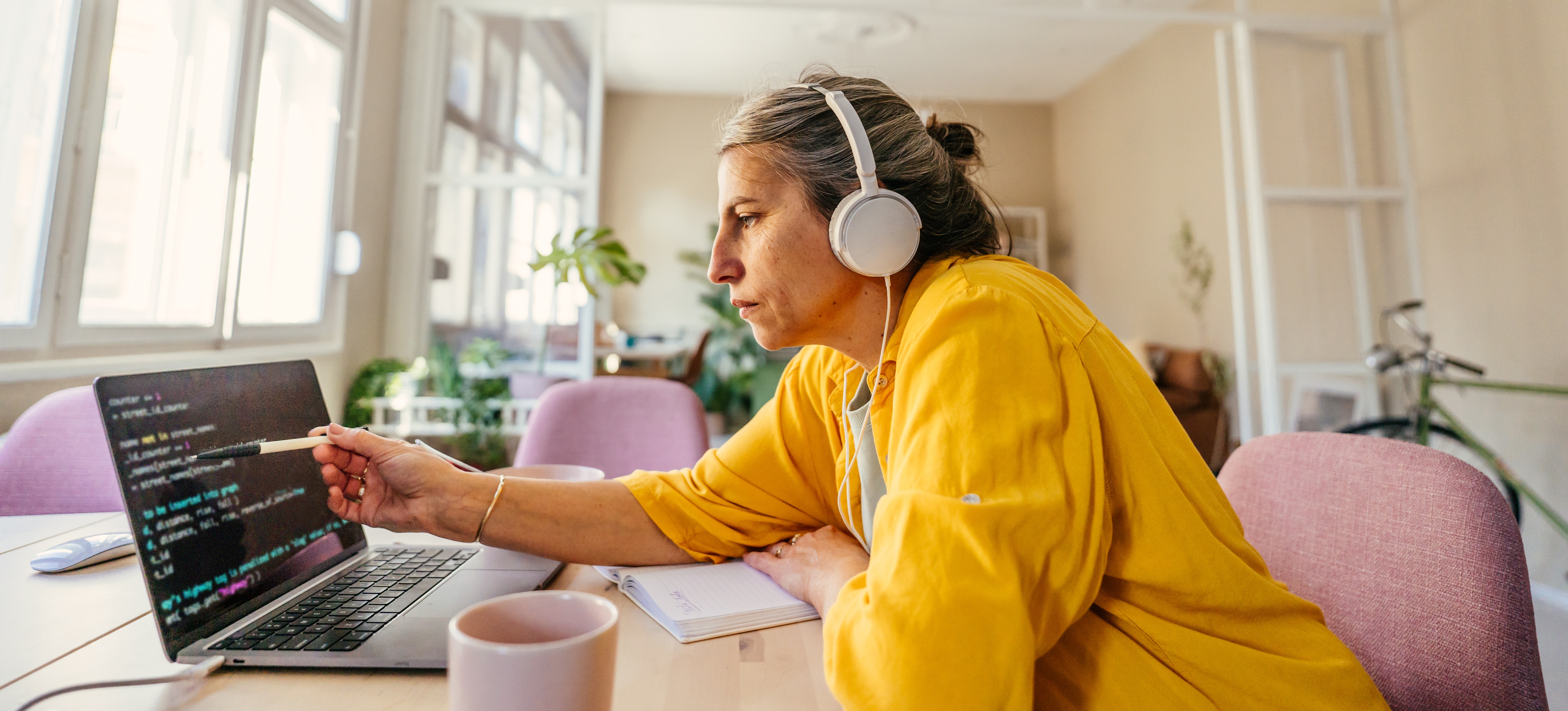 [Featured Image] An algorithm developer sits at a workspace, coding on a laptop.