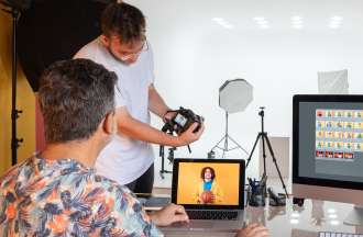 [Featured Image] A photographer and a video editor, who earns a video editing salary, work together on a photo shoot.
