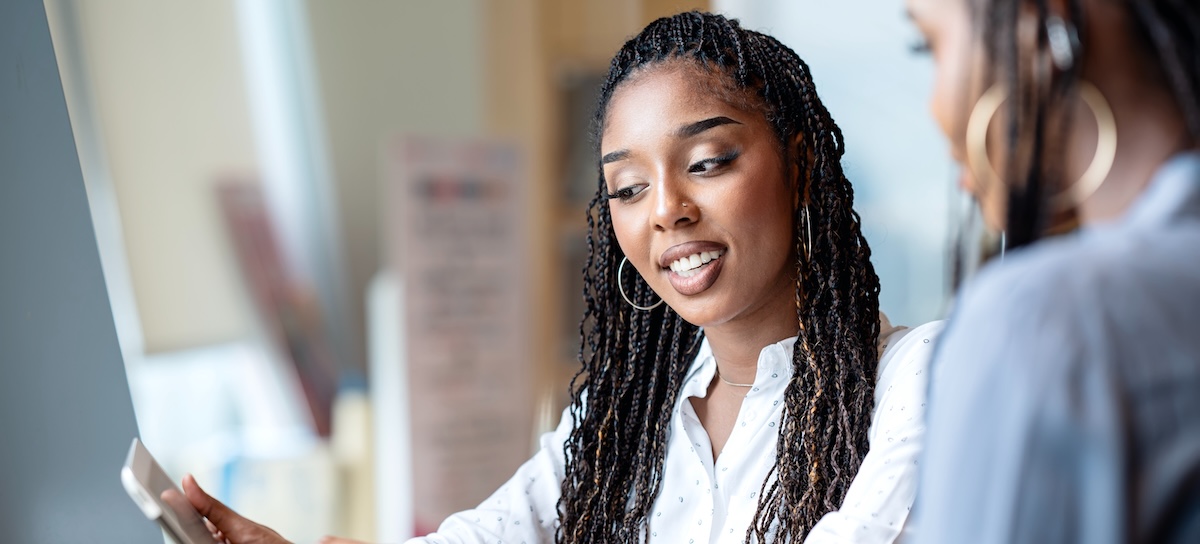 [Feature Image] A college learner explores small business accounting as a possible career path while researching options on a tablet and talking to their mentor.

