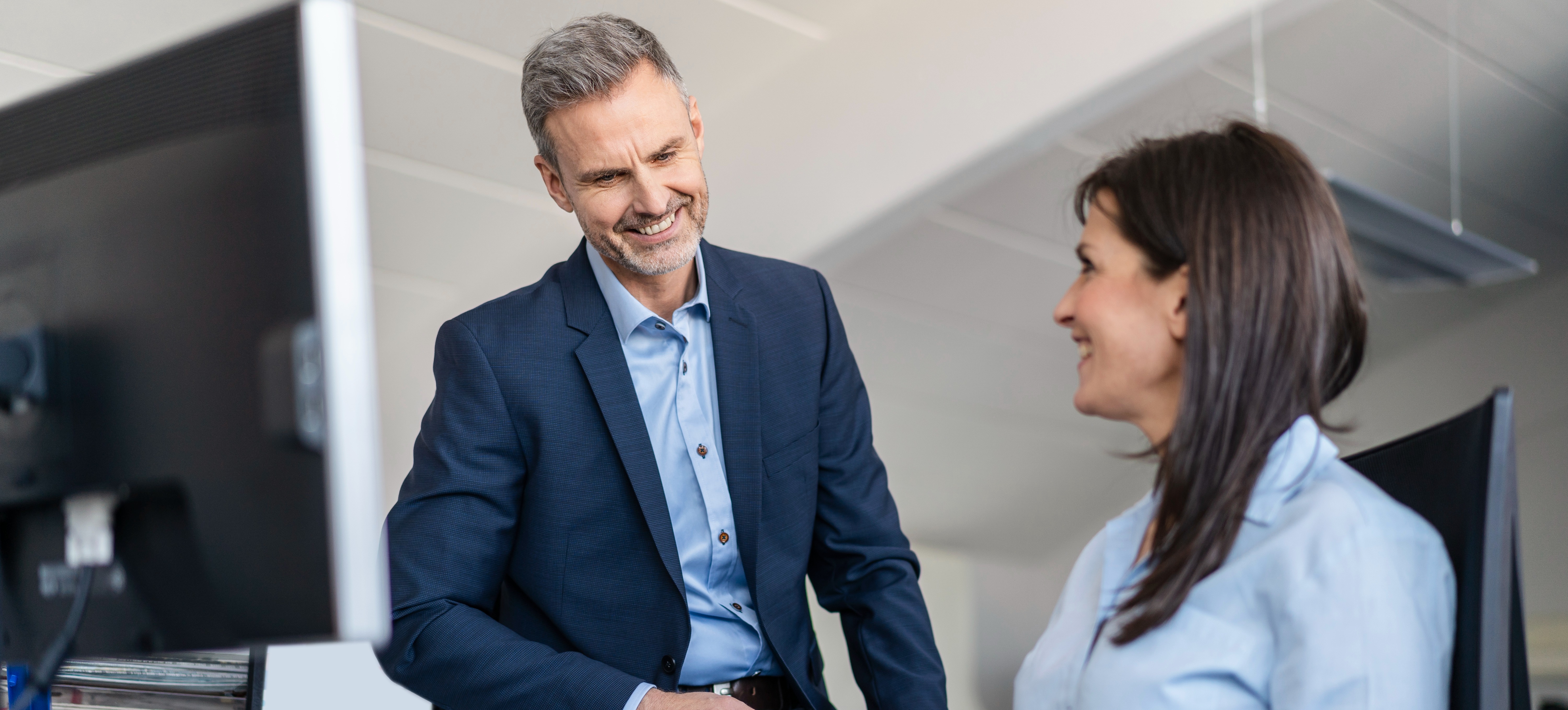 [Featured Image] A solutions architect in a professional workspace, interacting with a colleague while discussing certifications for solutions architects.
