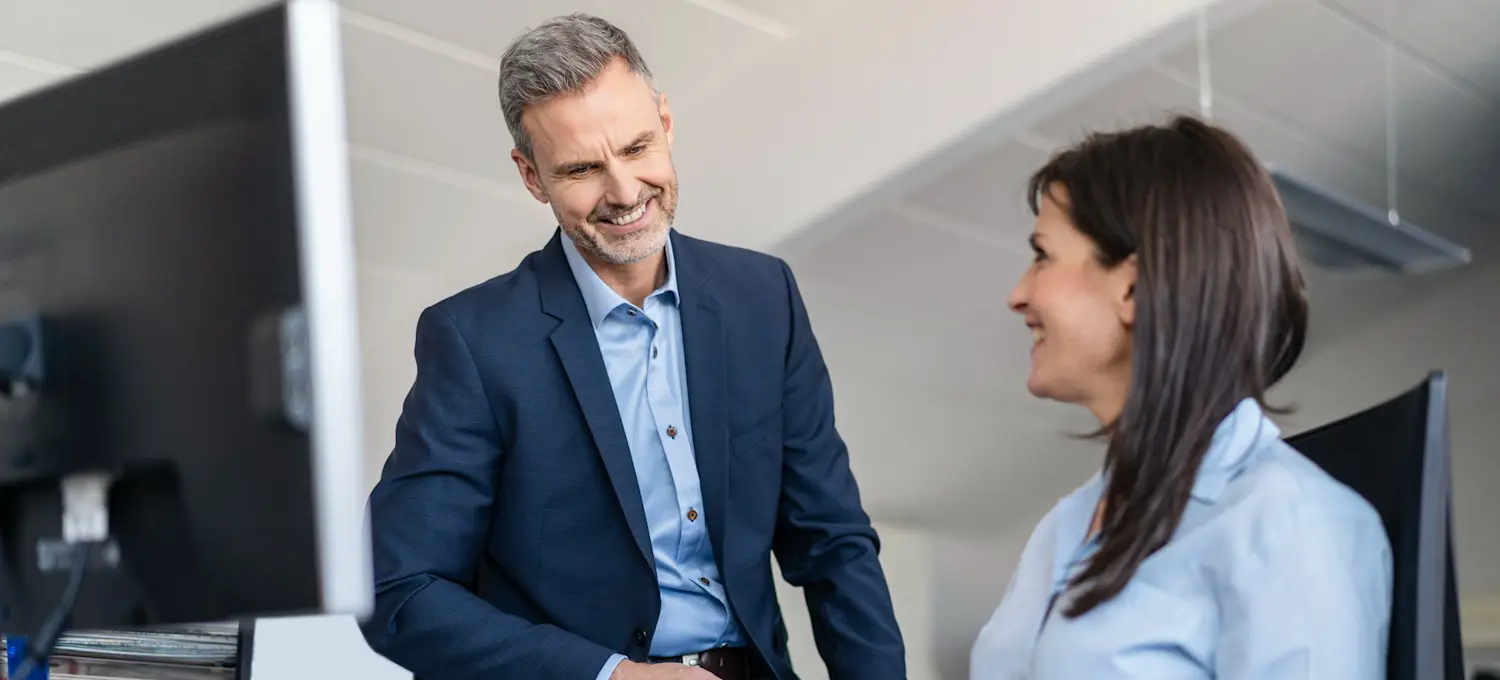 [Featured Image] A solutions architect in a professional workspace, interacting with a colleague while discussing certifications for solutions architects.
