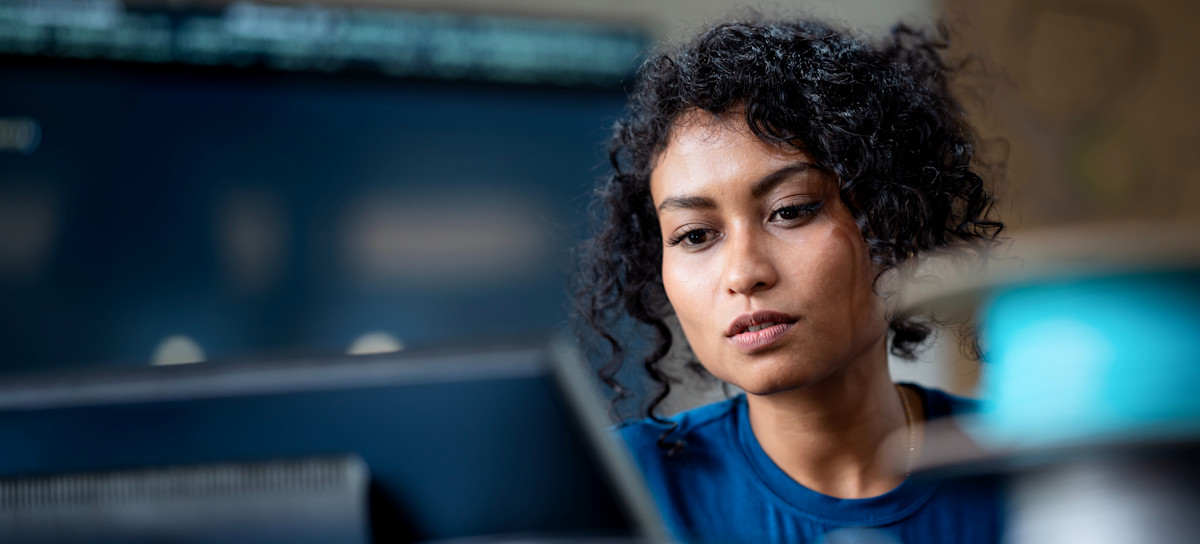 [Featured Image] A cloud security architect earning a CCSP salary concentrates as they look at a computer screen.
