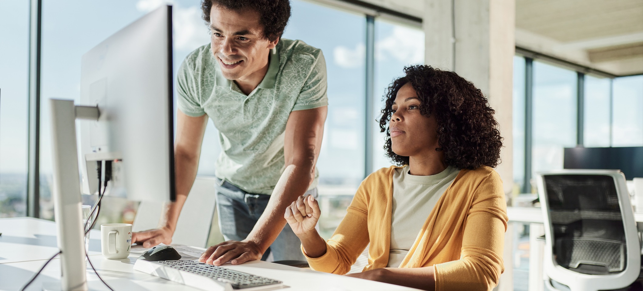 [Featured Image]: Two web developers work together at a computer on React projects for beginners.

