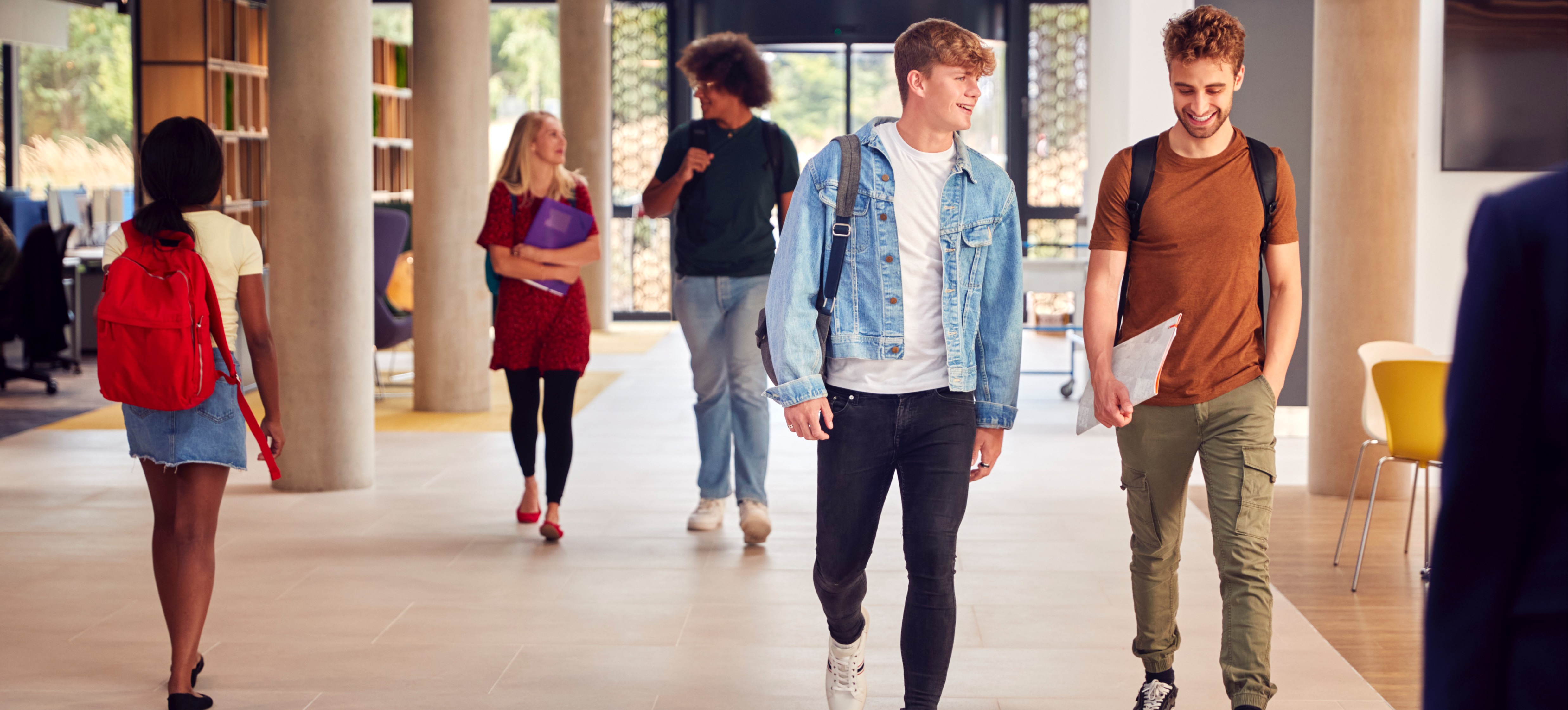 [Featured Image]: Uni students walk in the corridor of a university building after gaining admission to universities that do not require A levels.
