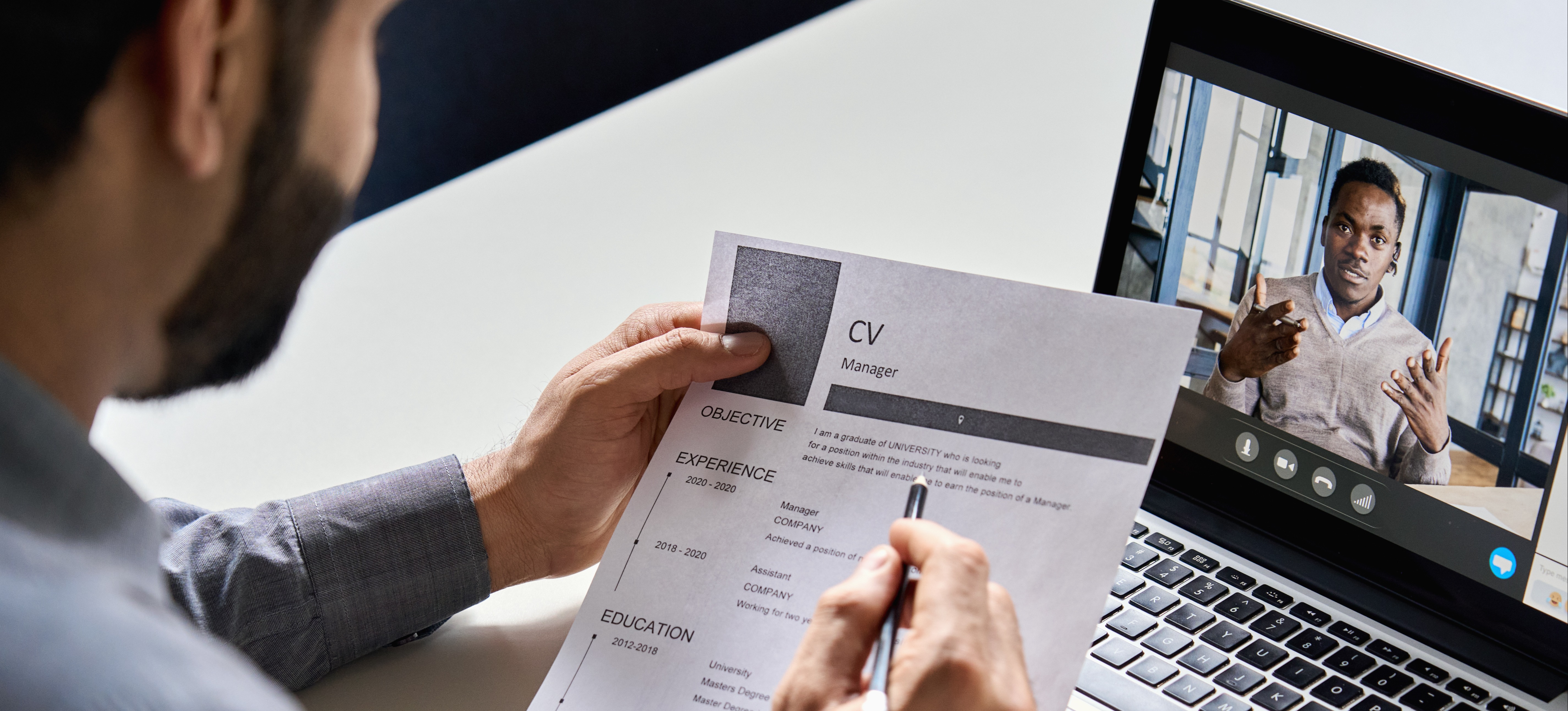 [Featured image] Hiring manager reviewing a CV while conducting a video interview with an applicant 