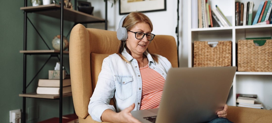 [Featued image] Woman sits on her couch at home with her laptop Googling how to create Shopify NetSuite integration