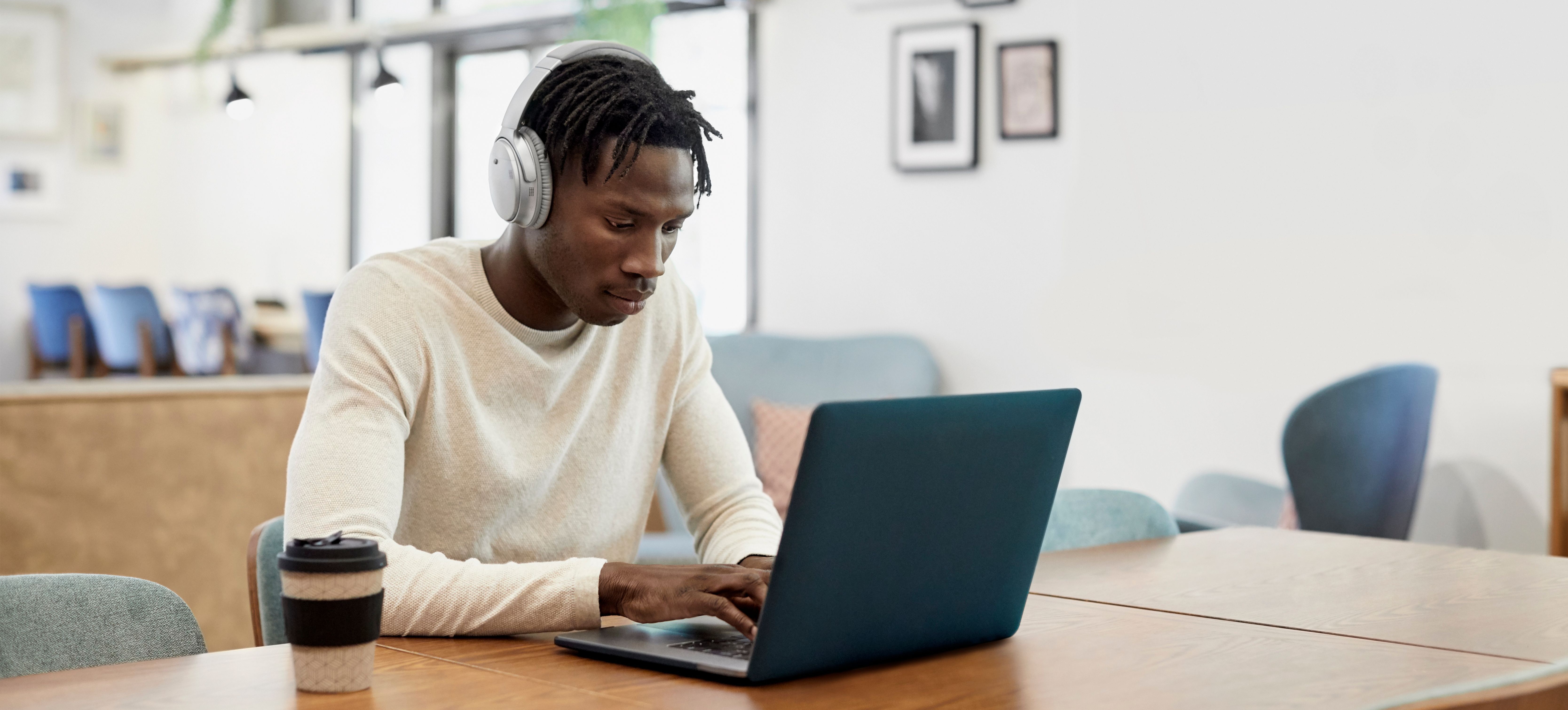 Un spécialiste de l'assistance informatique lit les adresses MAC sur son téléphone tout en marchant et en tenant une tasse. 