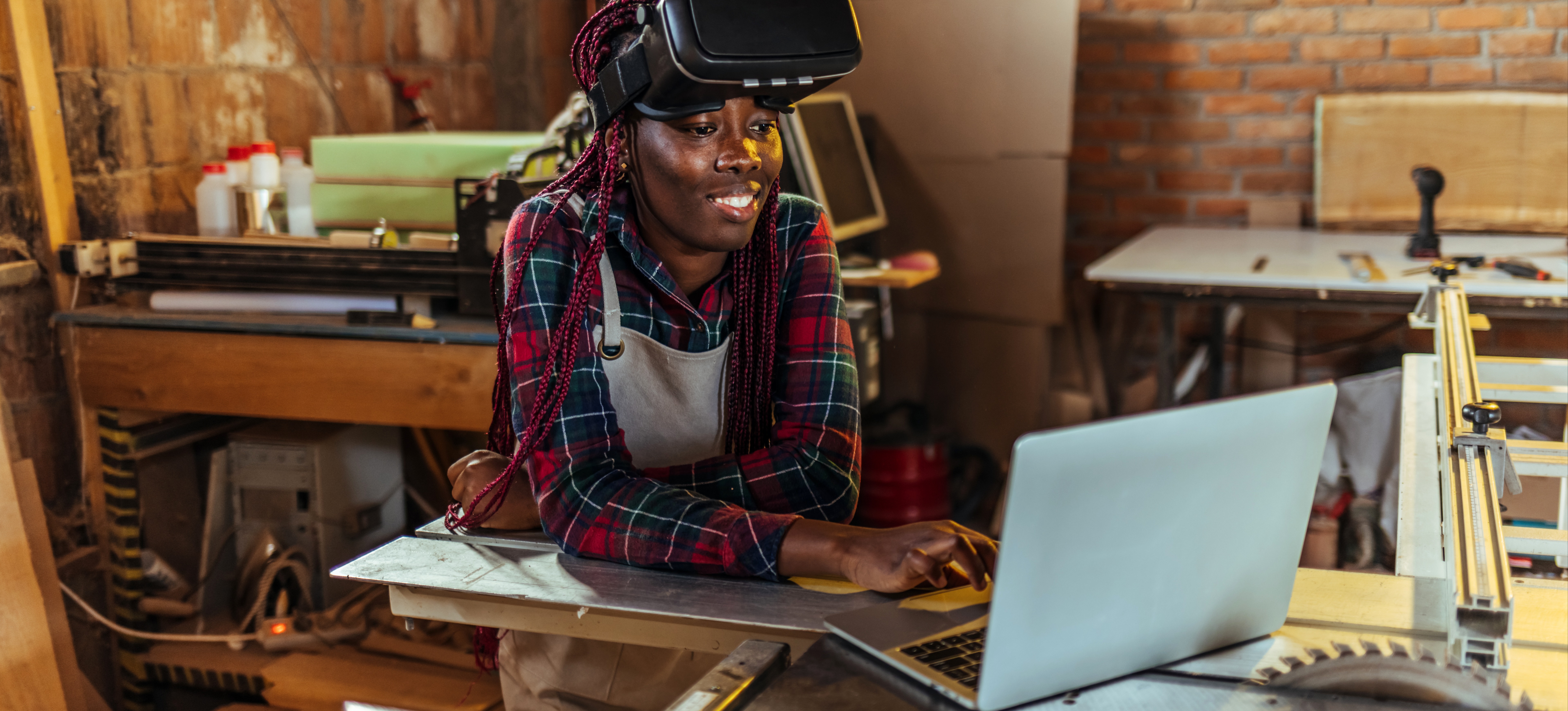 [Featured Image] An augmented reality developer leans on a worktable wearing AR glasses on the top of her head while she prepares for augmented reality interview questions on her laptop.
