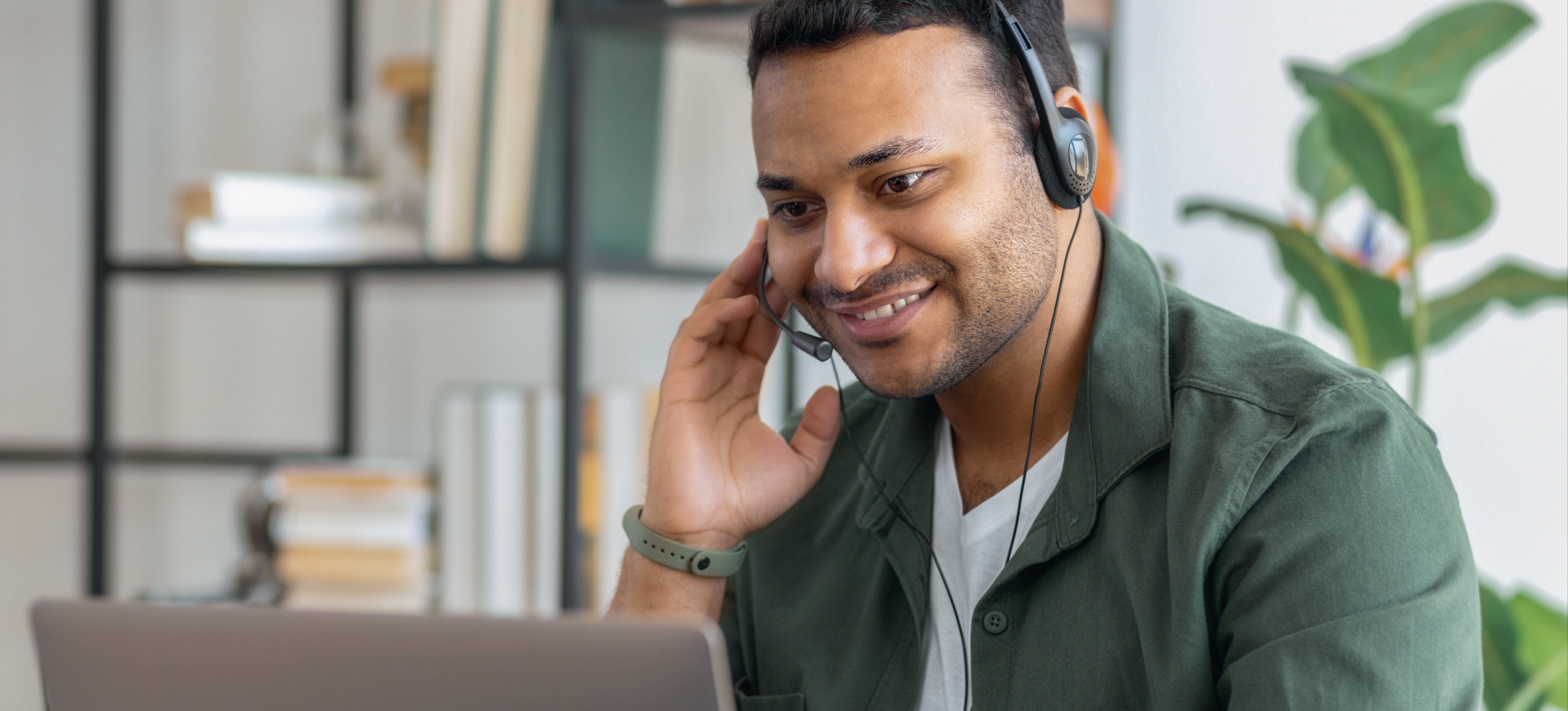 [Featured Image] A salesperson looks at a laptop and uses a headset to reach potential clients, step two of the sales cycle. 
