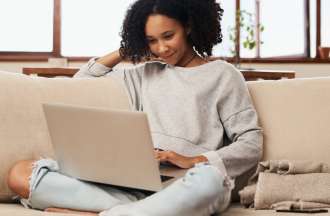 [Featured image] A woman looks up the CCNA certification at home on her laptop.