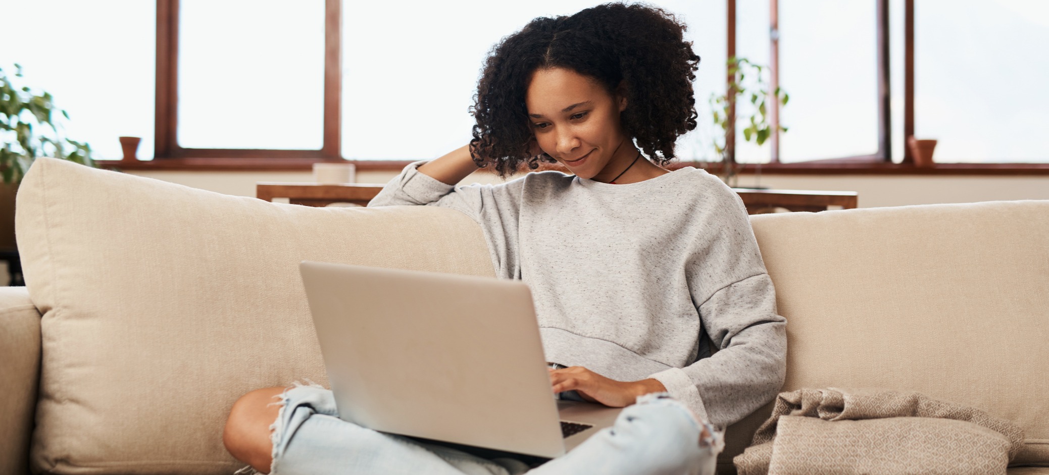 [Featured image] A person works on her MBA resume on a laptop while sitting on a sofa