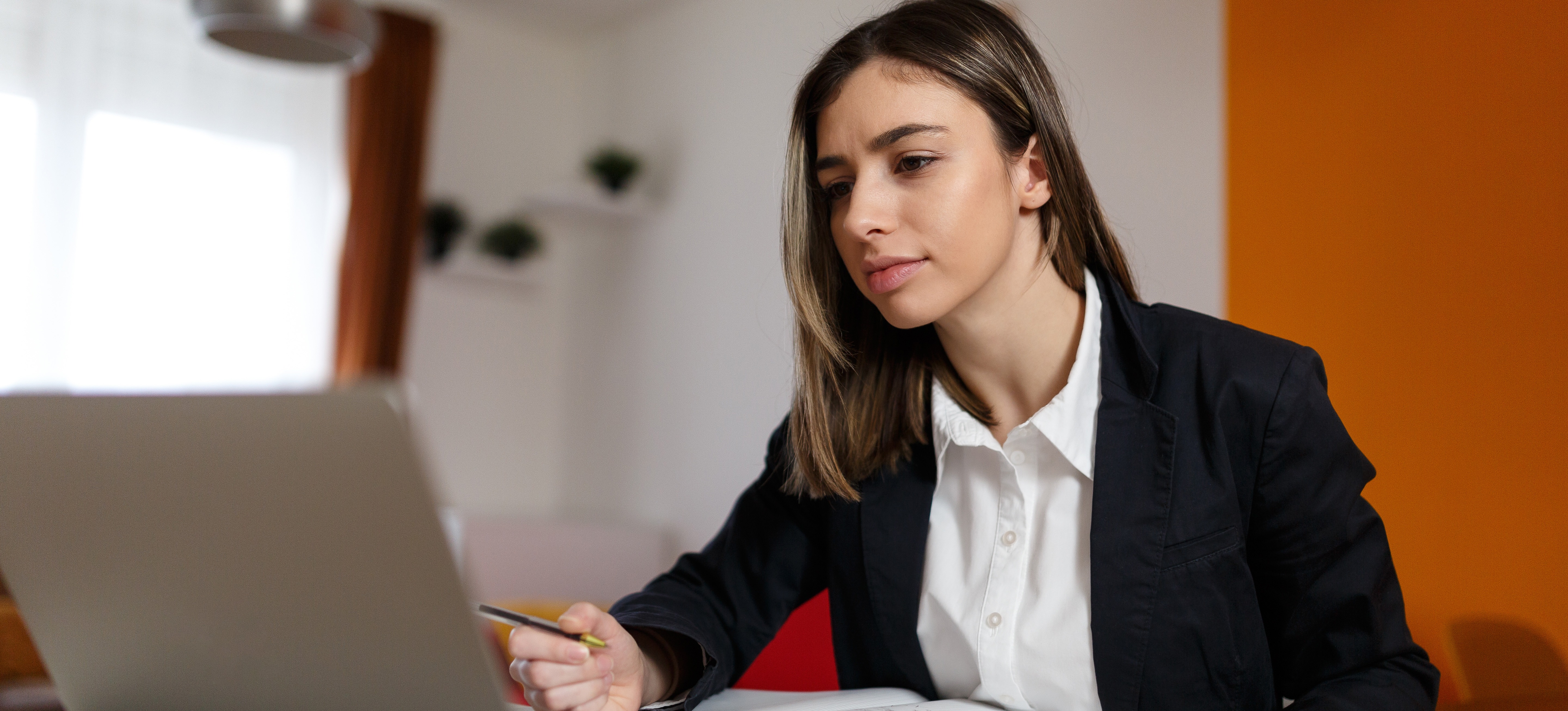 [Featured Image] A professional sits at a desk with a laptop and an exam guide, studying to become a certified project manager.
