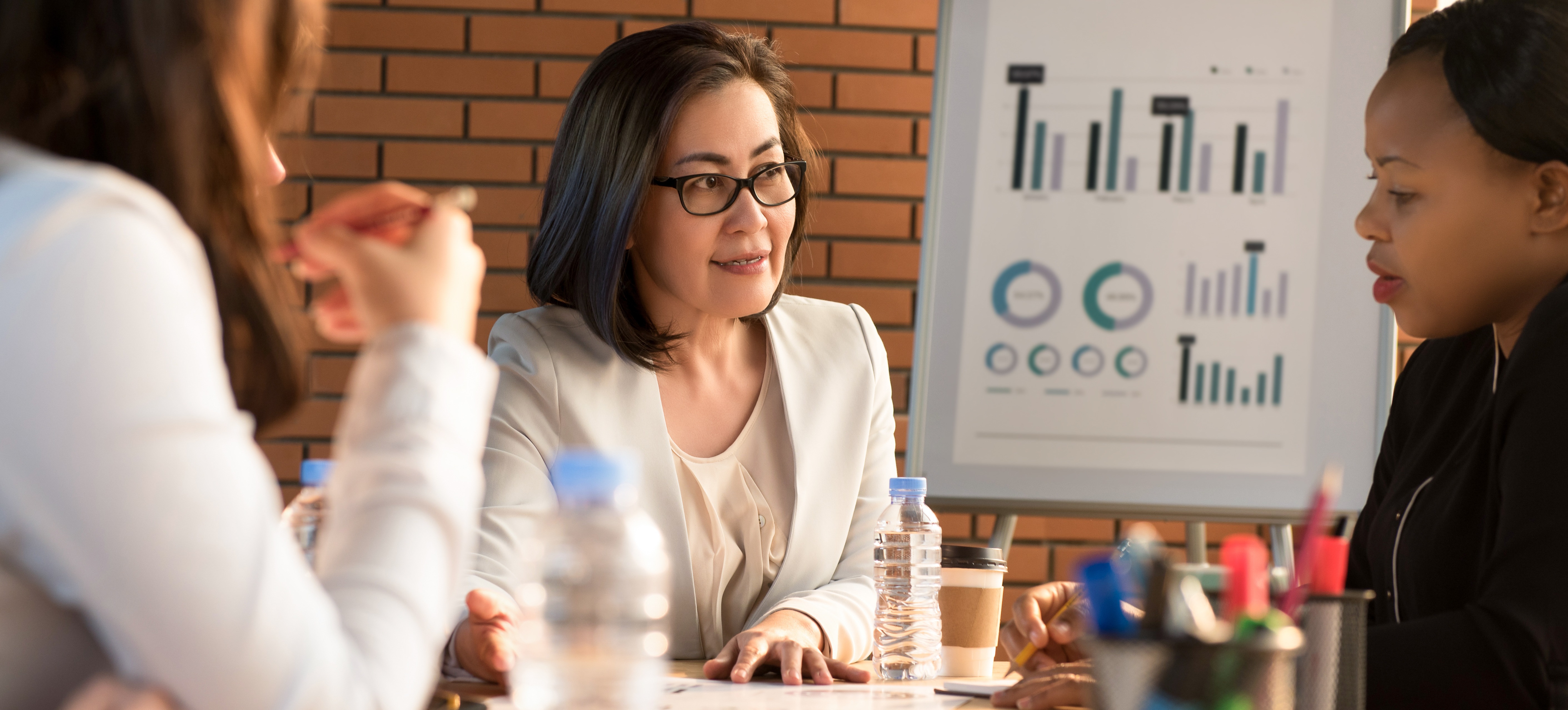 [Featured Image] A group of colleagues sit around a desk, discussing the data governance strategy for their organization.
