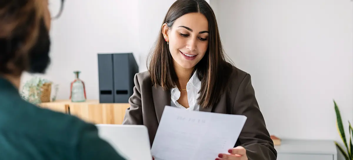 [Featured Image] A recruiter reviewing a candidate's resume in a professional setting, emphasizing the importance of showcasing R programming skills to secure a job in the field.