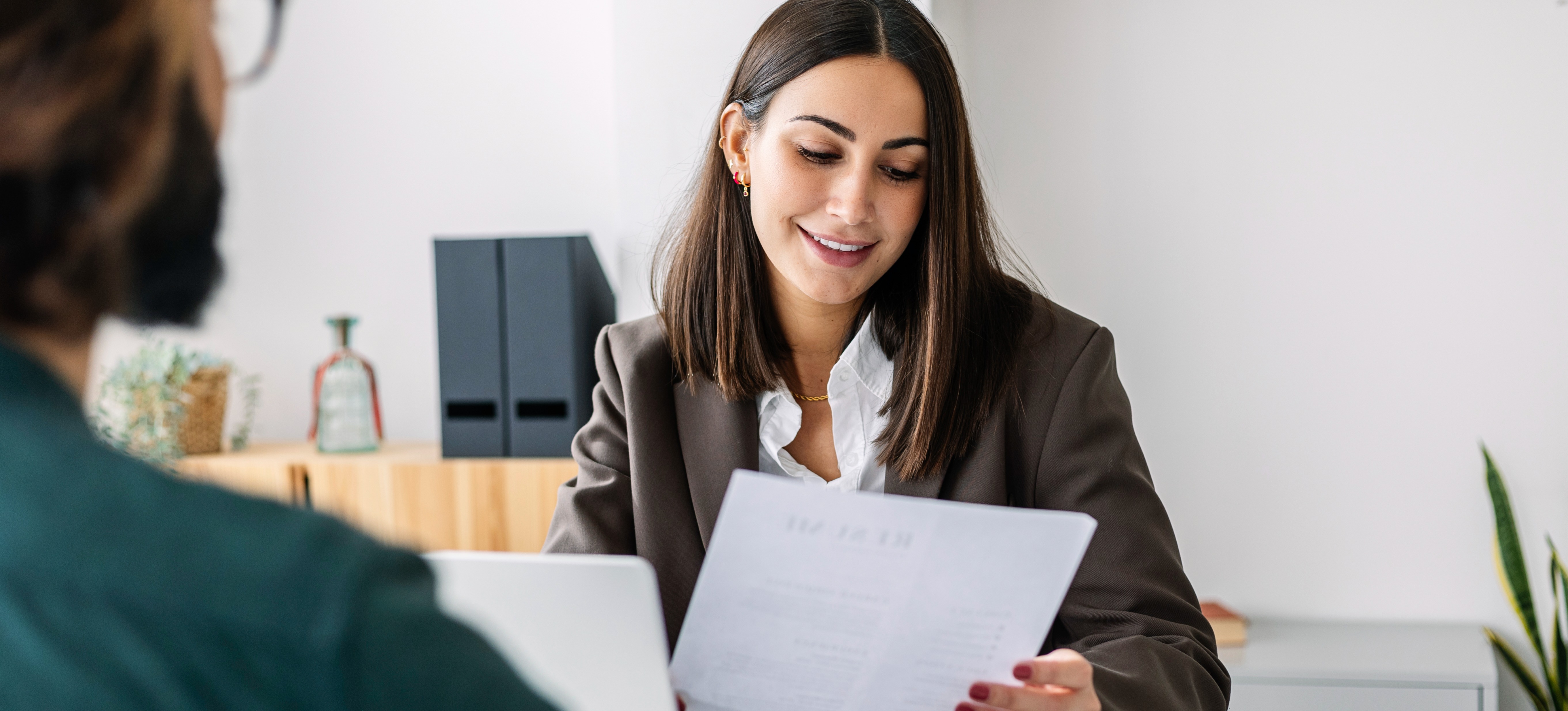 [Featured Image] A recruiter reviewing a candidate's resume in a professional setting, emphasizing the importance of showcasing R programming skills to secure a job in the field.