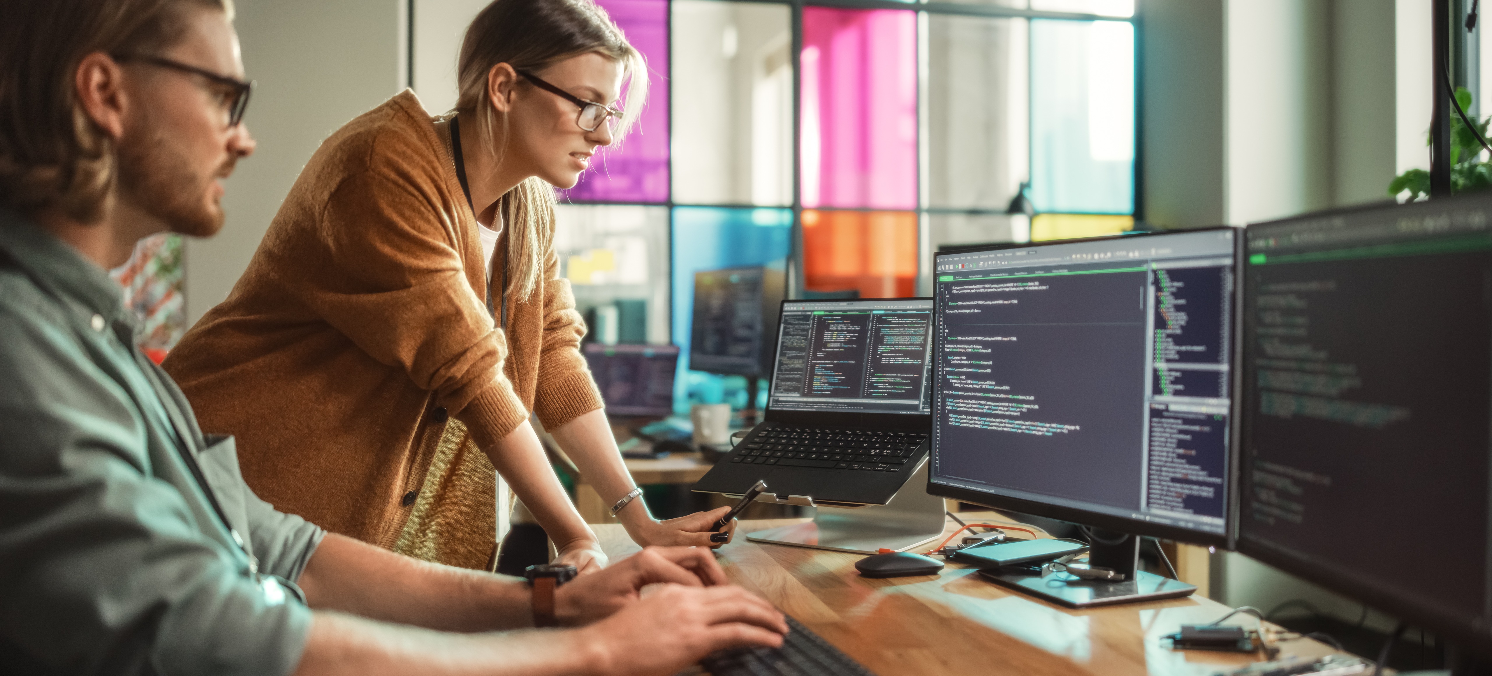 [Feature image]: Two engineers dive into the world of machine learning vs. AI as they work on a computer.

