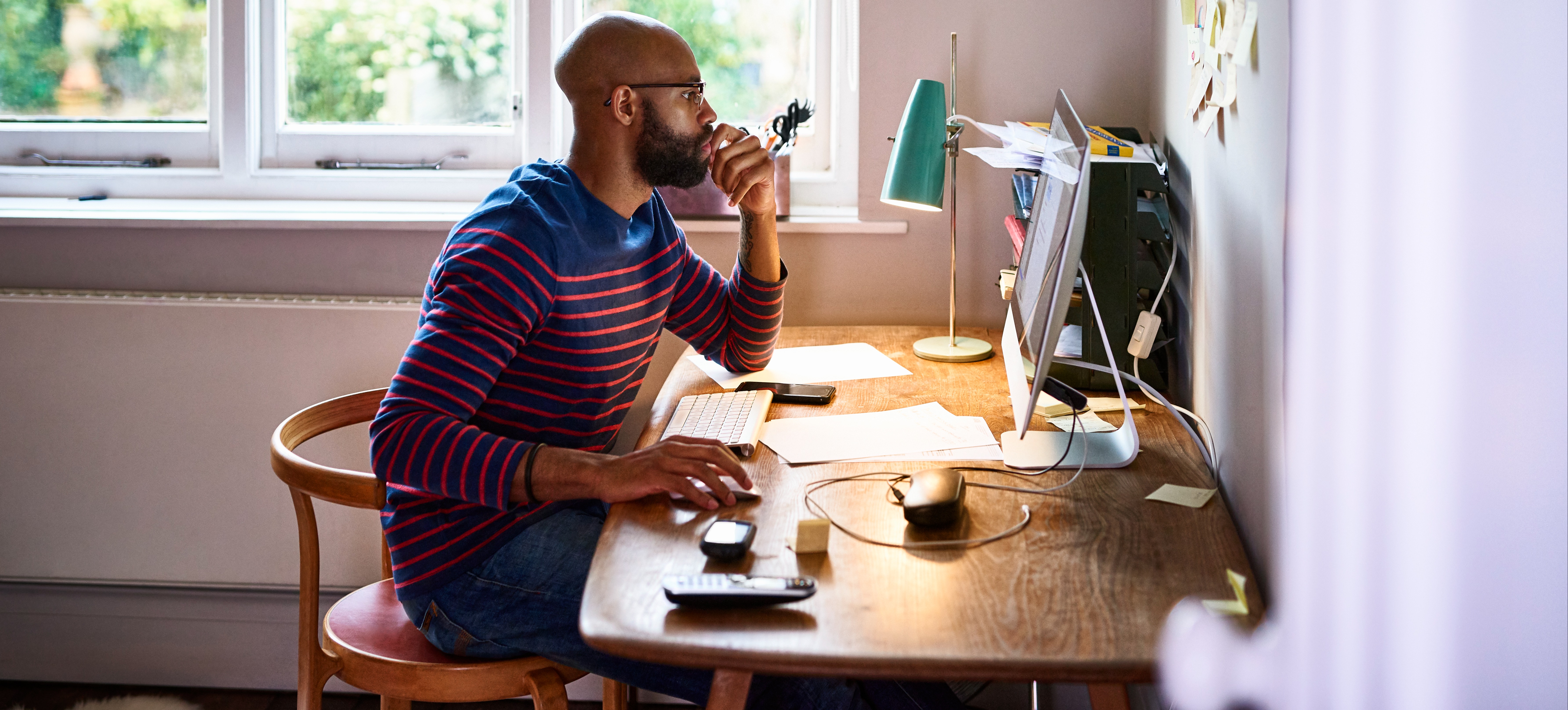 [Featured Image] A person is sitting at their desk using a desktop to research climate change jobs.