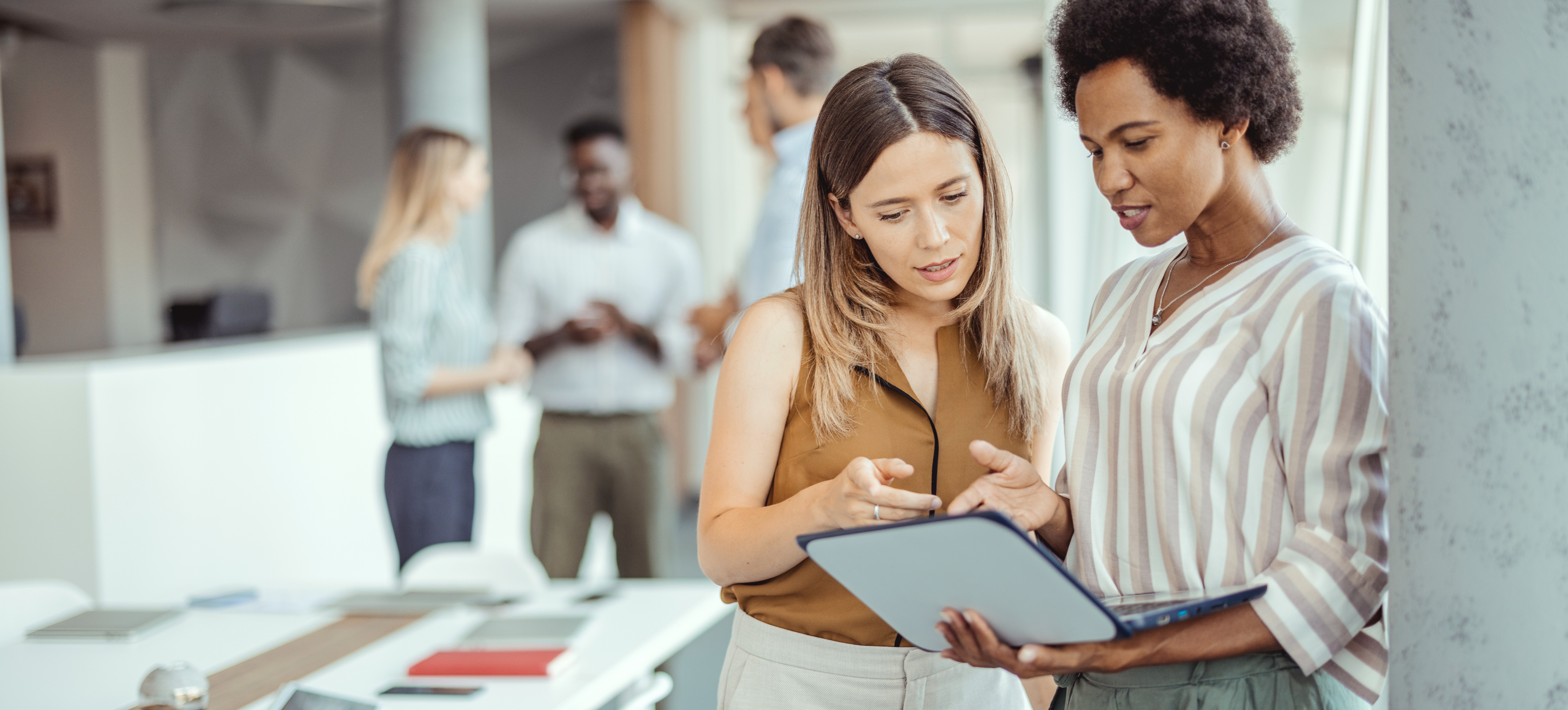 [Featured Image] Two colleagues confer about their process mapping system and work together to use it to identify areas for the company to improve. 
