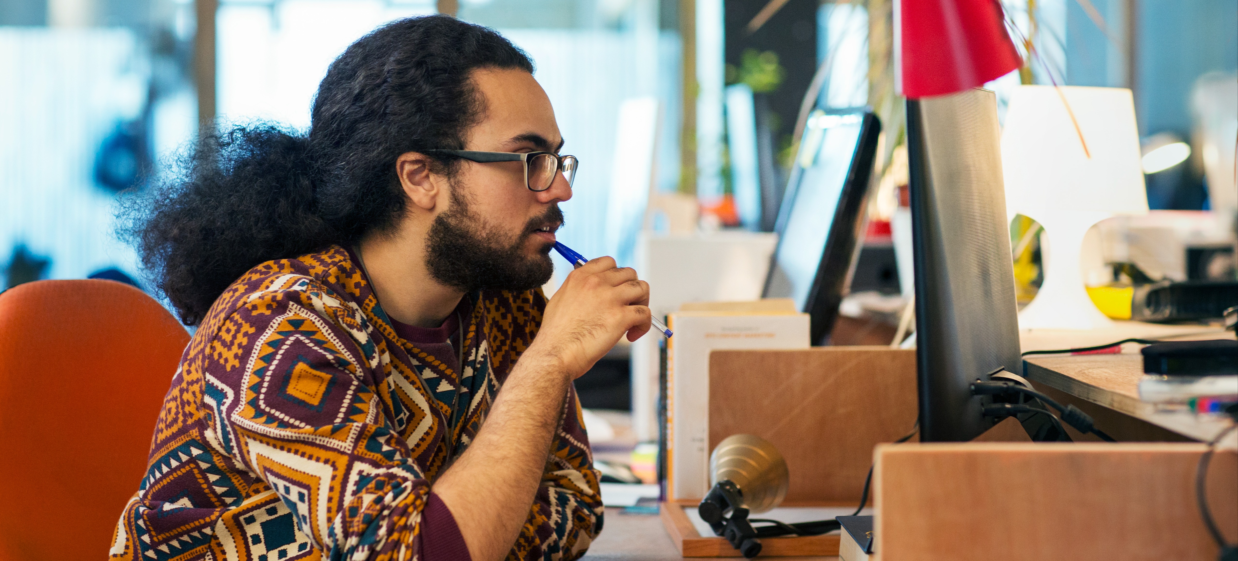 [Featured Image] A UX designer sits at a workspace and uses AI to help streamline their processes.
