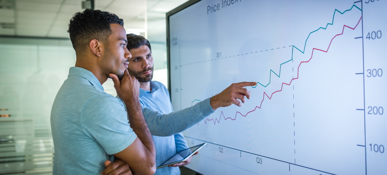 [Featured image] Two men stand in a conference room looking at a chart showing rising growth, questioning which degree makes the most money.