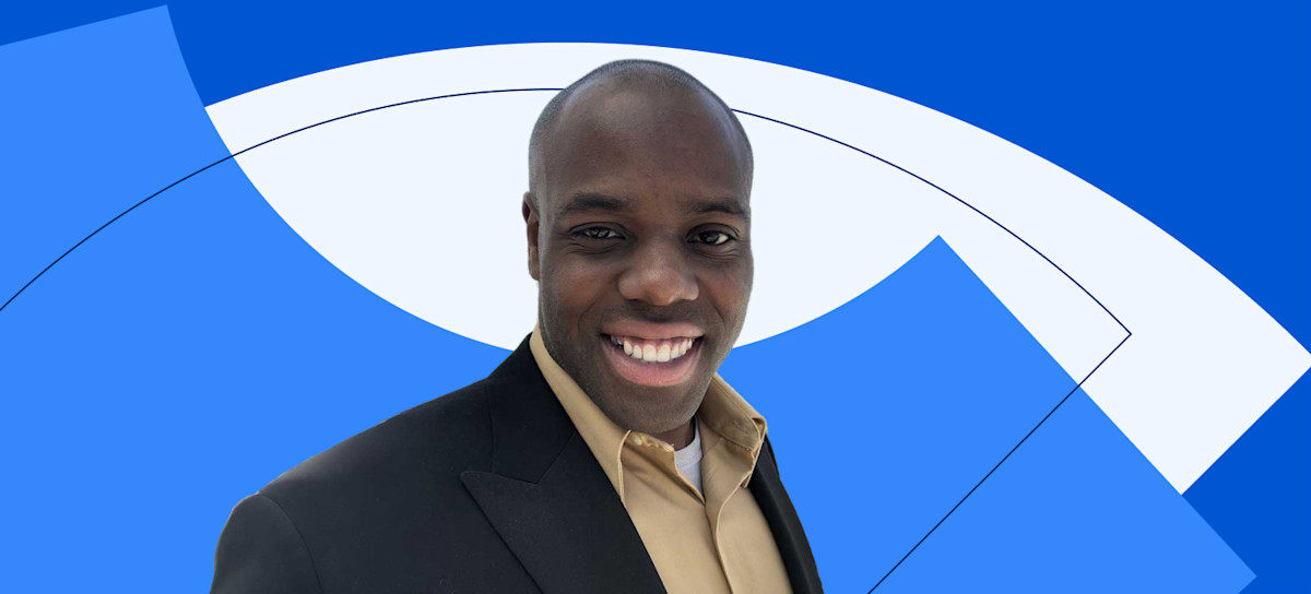 [Featured image] Coursera Plus learner Andre King smiles in front of a Coursera blue background.
