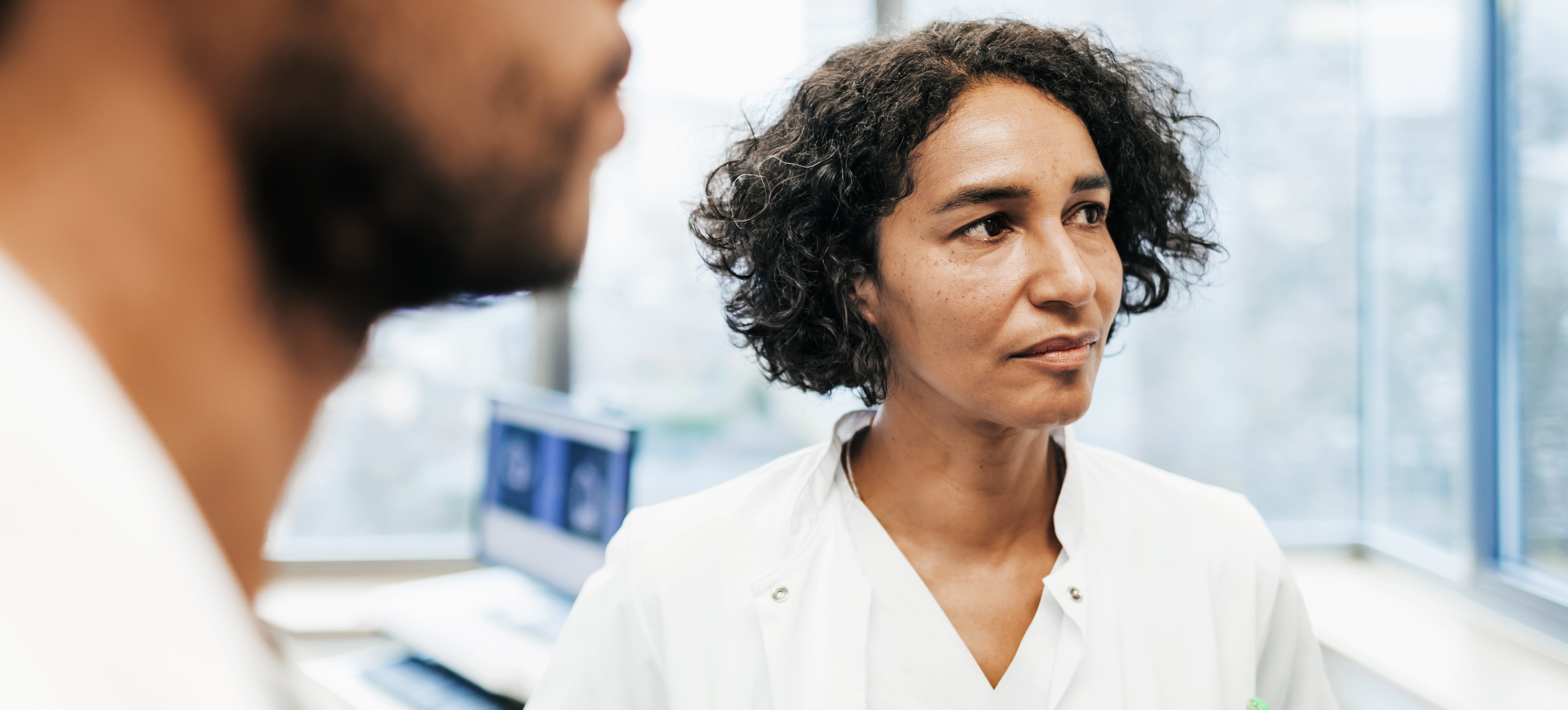 [Featured Image] A clinical manager in a white medical coat stands in a clinic. 