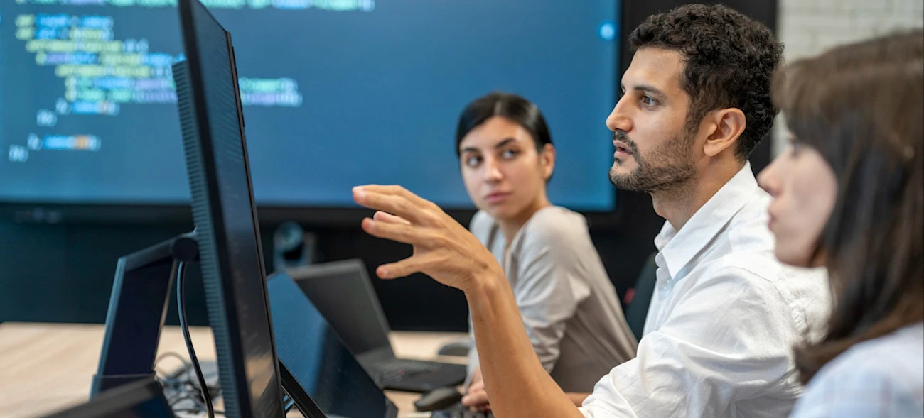 [Featured Image]: Three people sitting at a table discuss alternatives to Papers With Code as they plan their next machine learning project.
