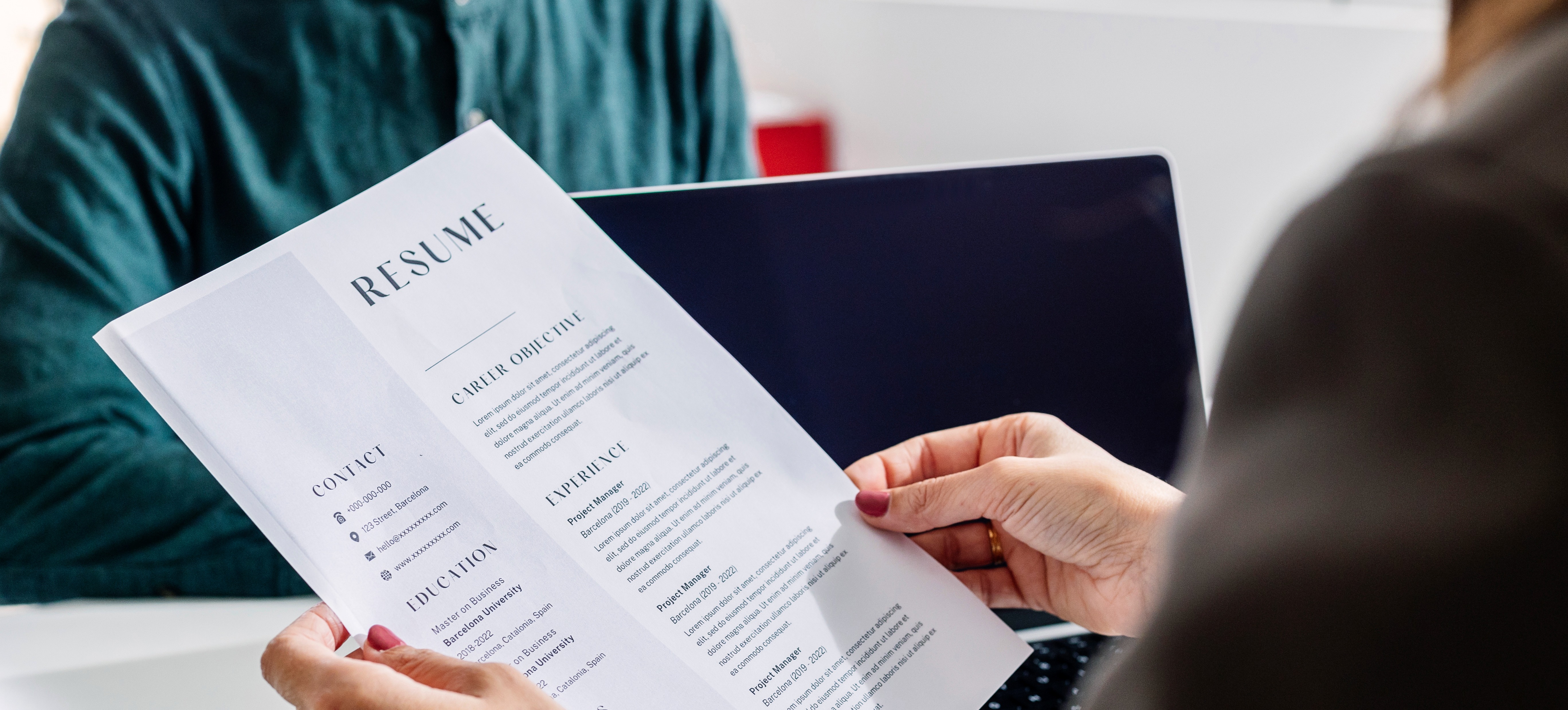 [Featured Image] A job applicant confidently hands in their HR resume to the hiring manager.
