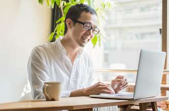 [Featured Image] A man works at a desk on a laptop computer.