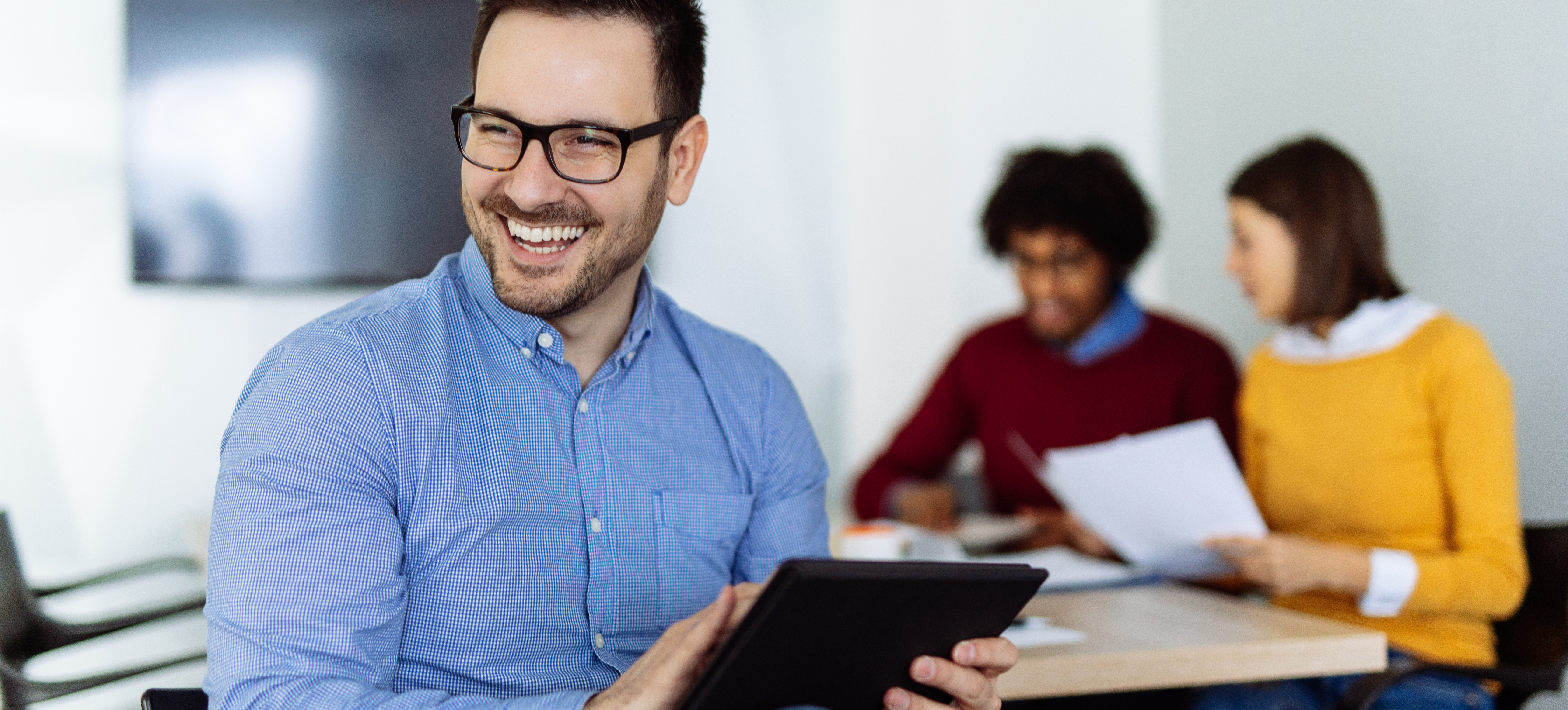 [Featured Image] A digital marketing student sitting with a tablet in a room of other students, celebrates qualifying for the AMA digital marketing certification.
