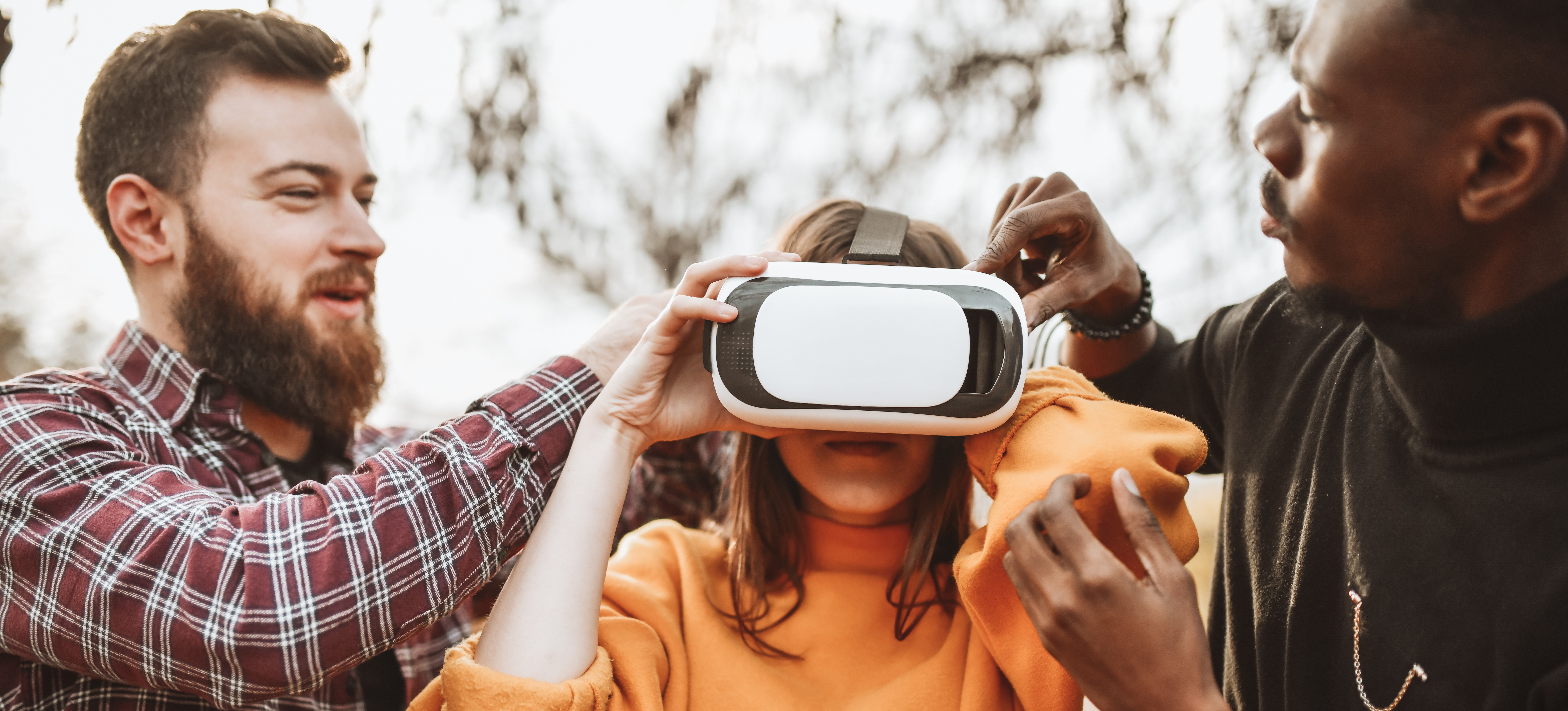 [Featured Image] A male realtor is showing a couple a property in another state by wearing a VR headset. 