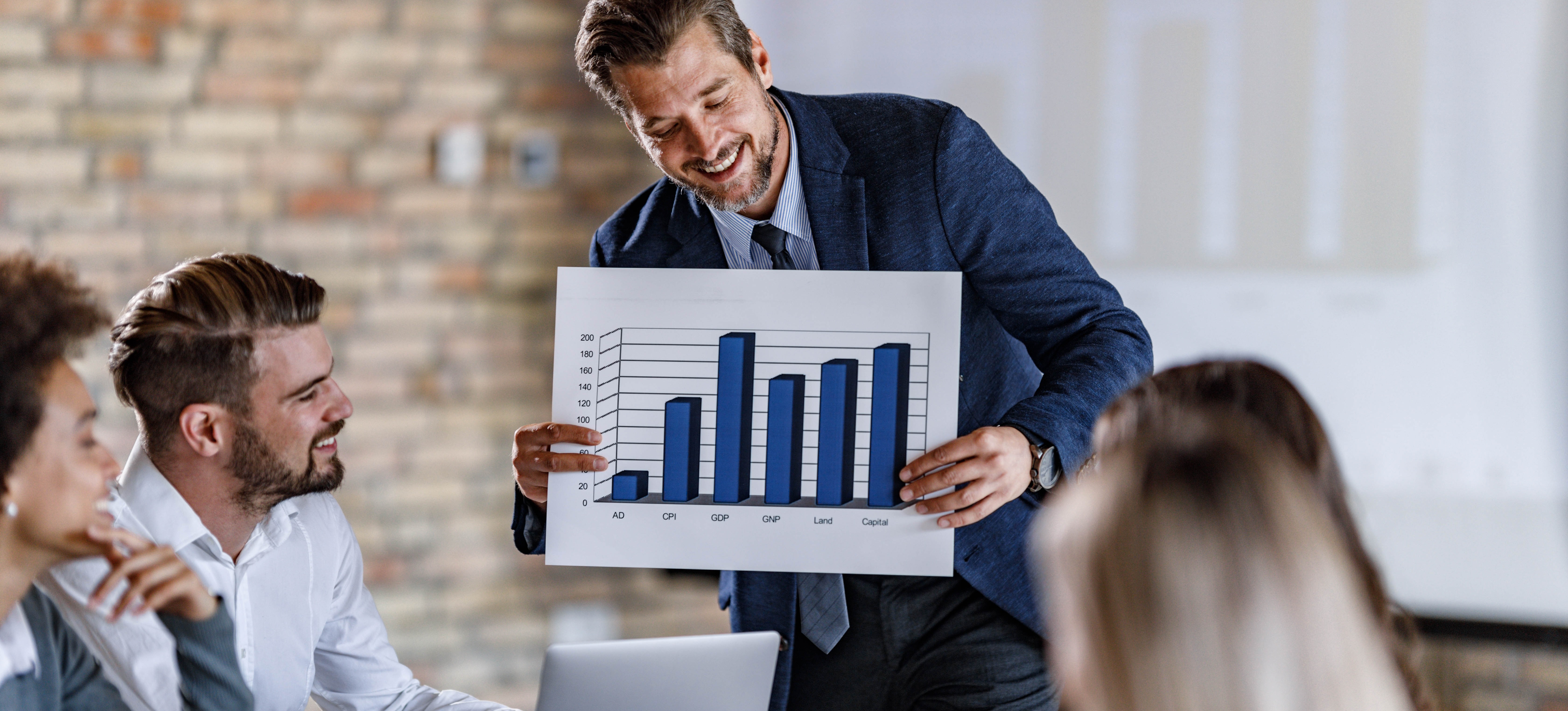 [Featured Image] A financial risk manager discusses financial risk management strategies with the team in a professional workplace setting.
