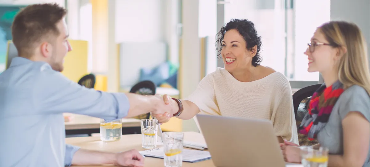 [Featured Image] Interviewers shake hands with a candidate in a professional work environment after reviewing their deep learning resume and discussing career opportunities.
