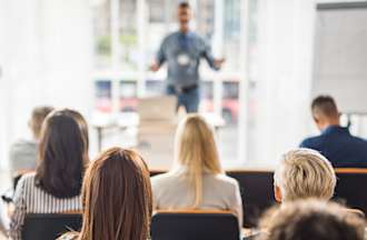 [Featured image] A group of employees attends a seminar on their company's new identity governance policies. 
