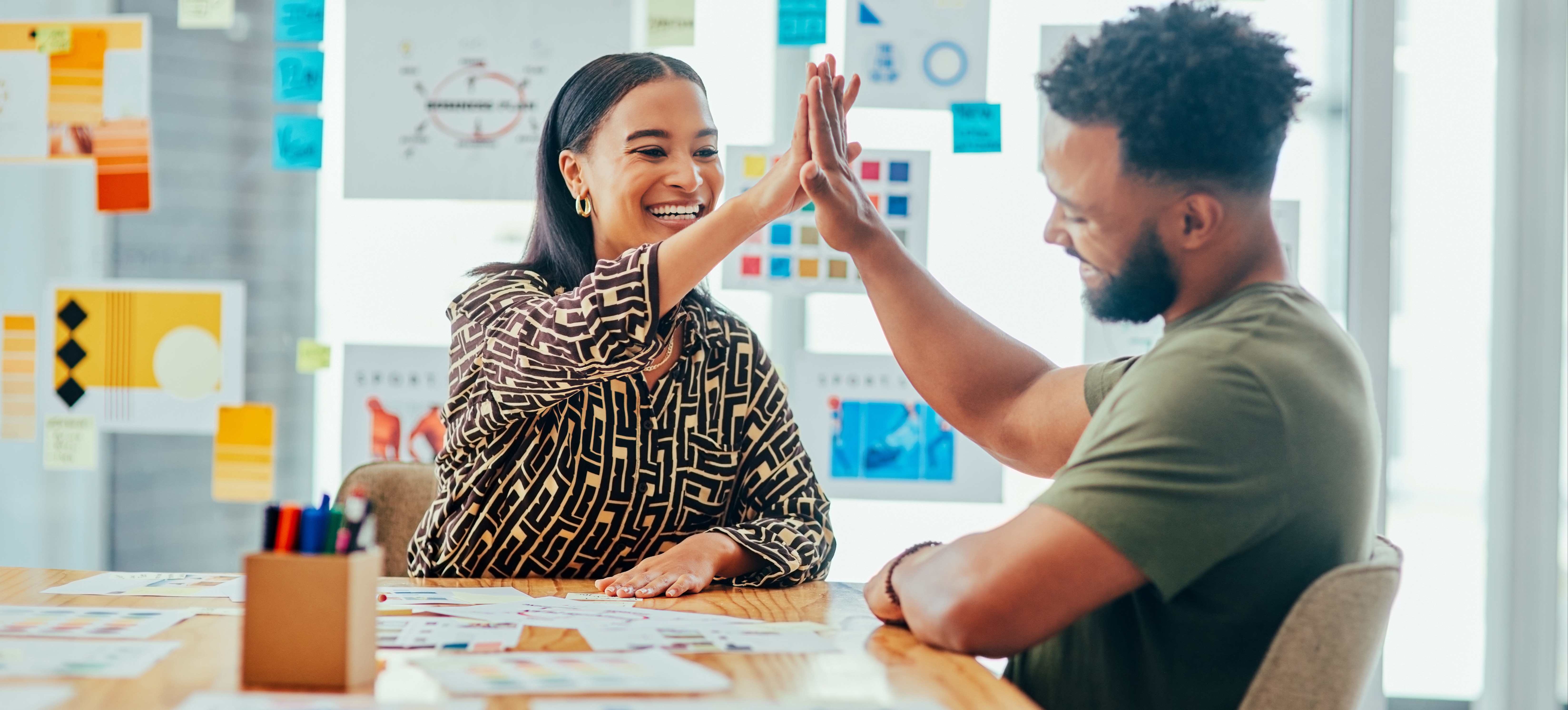 [Image en vedette] Deux spécialistes du marketing se félicitent mutuellement dans un espace de collaboration après avoir créé une campagne de marketing réussie.
