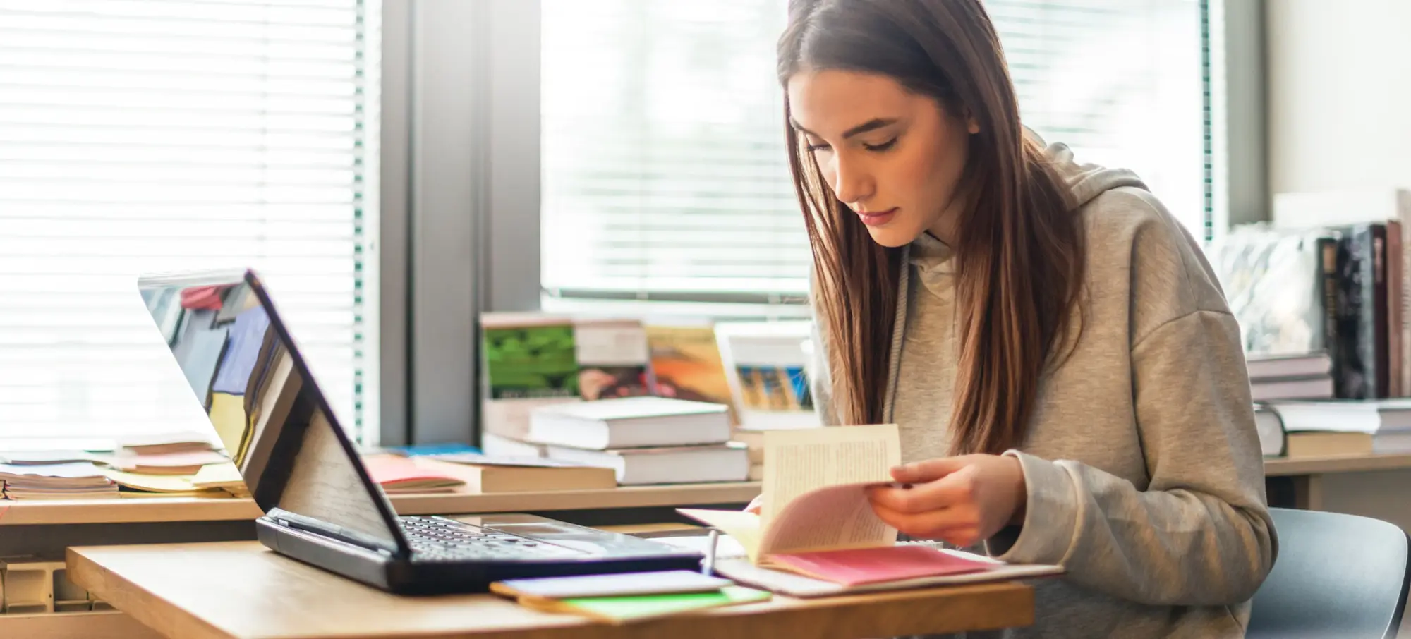 [Featured Image] A bachelor's degree student at a desk with a laptop computer and an open book.