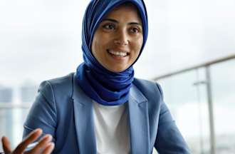 A social worker in a blue jacket with a scarf speaks with one of her patients in a brightly lit office.