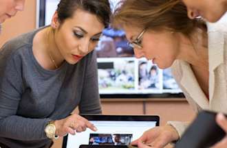 [Featured Image} A group of four tech professionals look at AI generated photos on a laptop and discuss generative AI models.