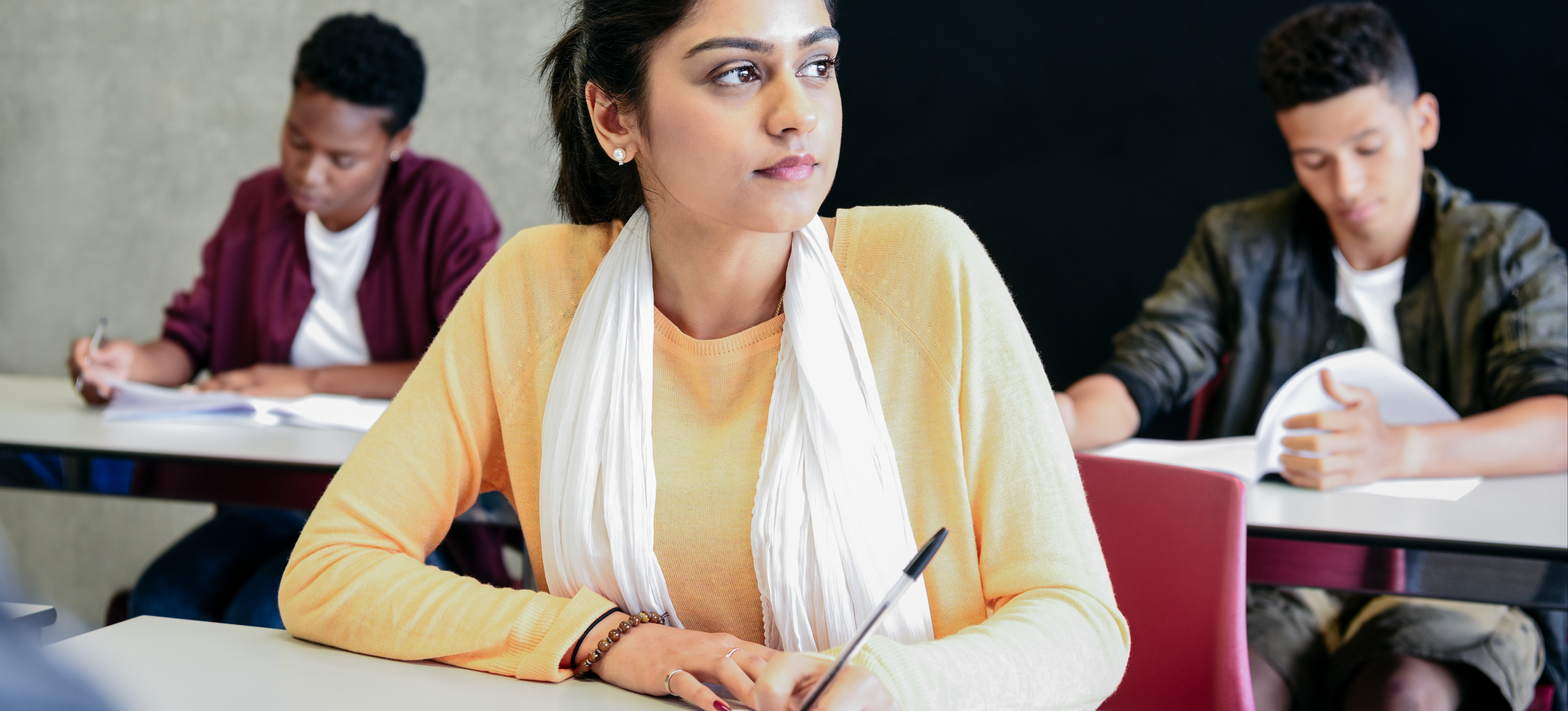 [Featured image] A learner in a yellow shirt and scarf sits at a desk preparing to take a college entrance exam.